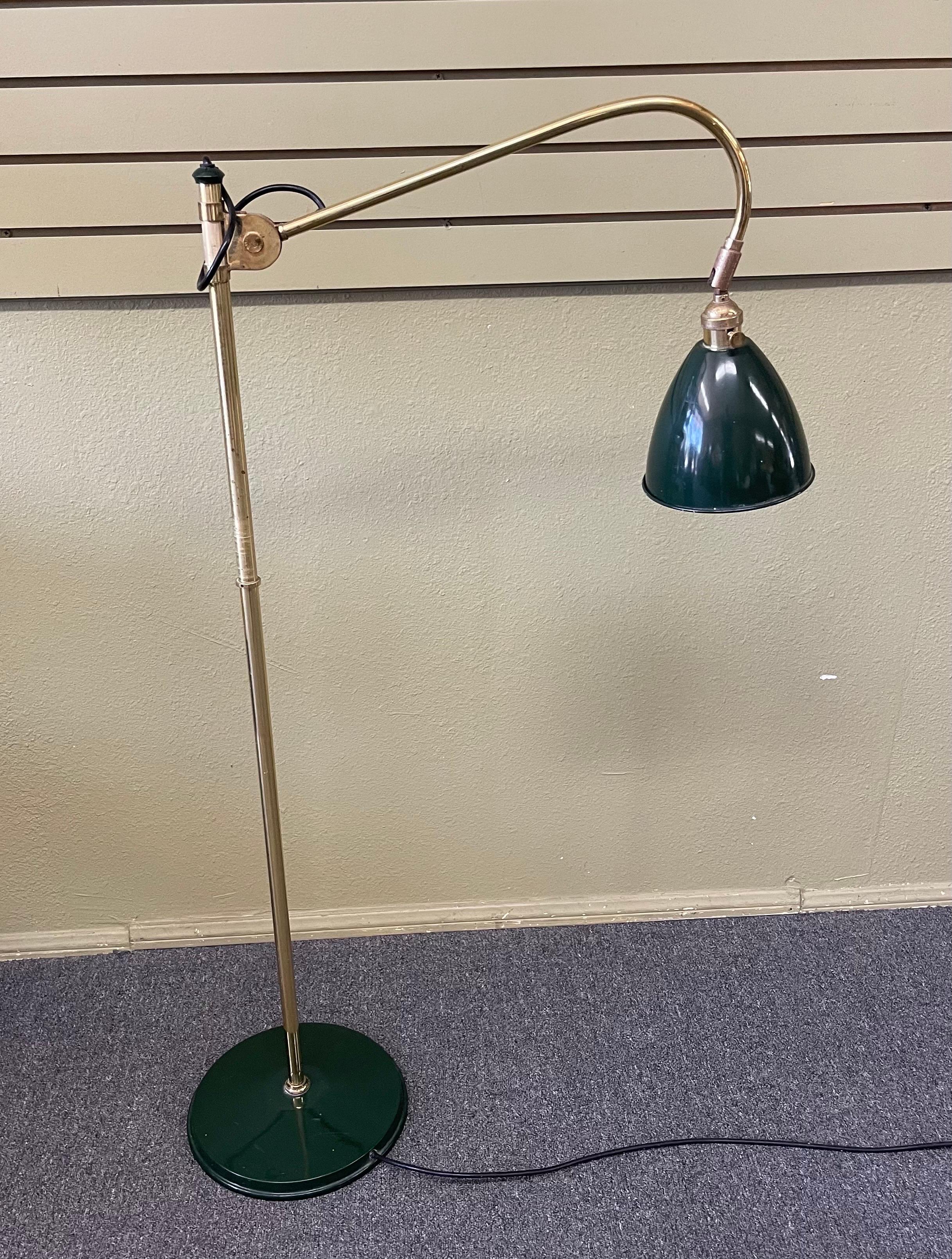 A very cool industrial architectural floor lamp by Louis Baldinger, circa 1980s. The piece is in good vintage condition and made of green painted sheet metal with brass accents and bars. The lamp is fully articulated at lamp hood and center of stem