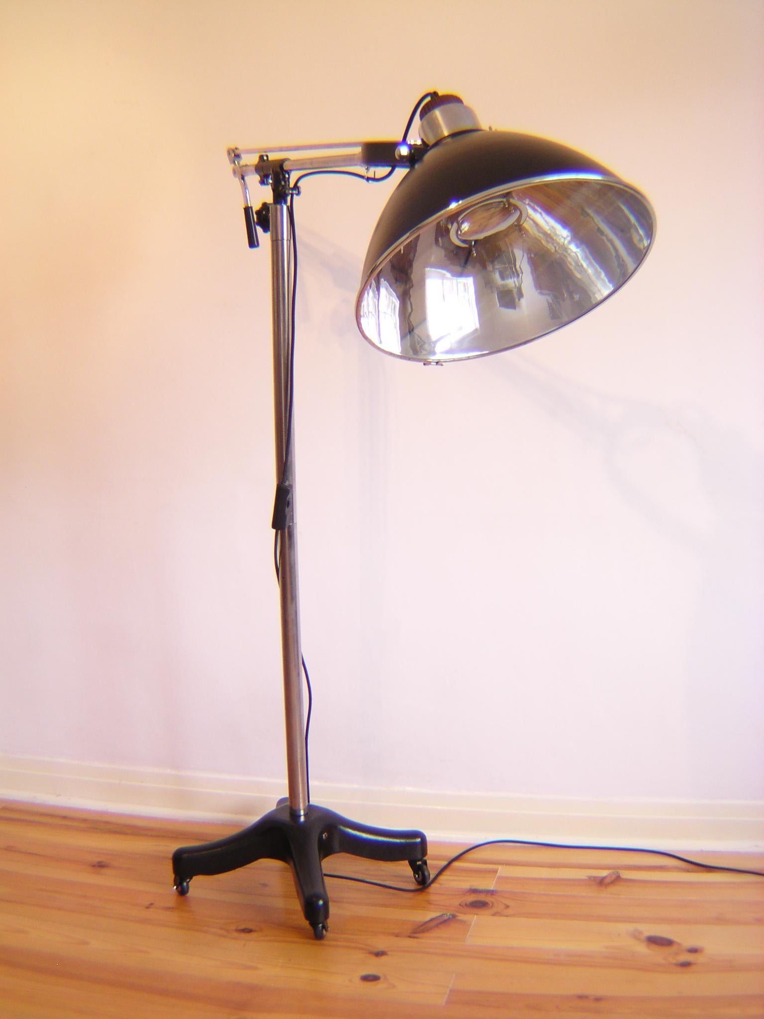 Lampe médicale sur pied transformée sur roues.
Abat-jour émaillé et corps noir (procédé de peinture industrielle au four)
Avec bras chromé rotatif et lumière. Possibilité de position suspendue
Recâblage avec câble noir isolé en coton, avec