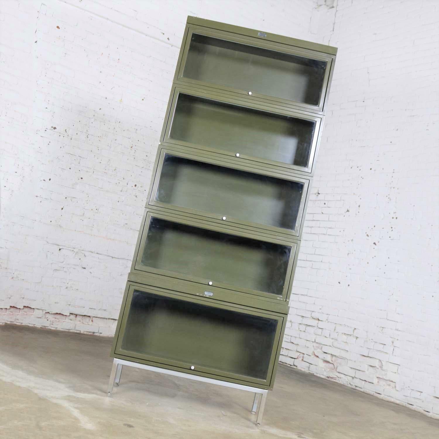 Awesome vintage Industrial metal barrister bookcase with five stacking sections plus a top and base. They still wear their original Army green painted finish and are in wonderful vintage condition. They are solid and sturdy but there may be some