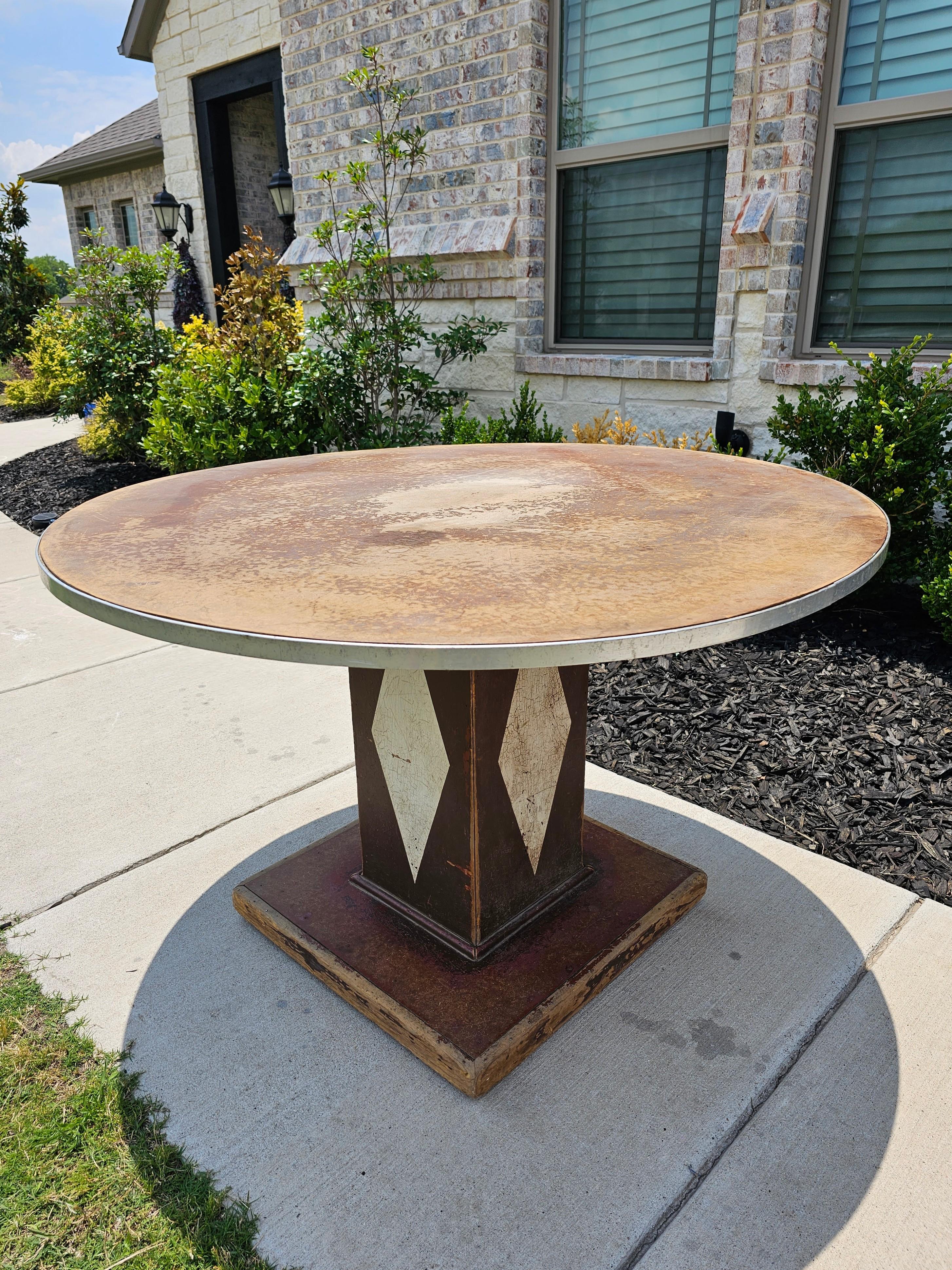 A fabulous Art Deco era industrial department store round display table. circa 1930s

Having a circular top with metal rim, rising on wooden pedestal support with painted diamond accents, atop sturdy square plinth base. 

Dimensions: