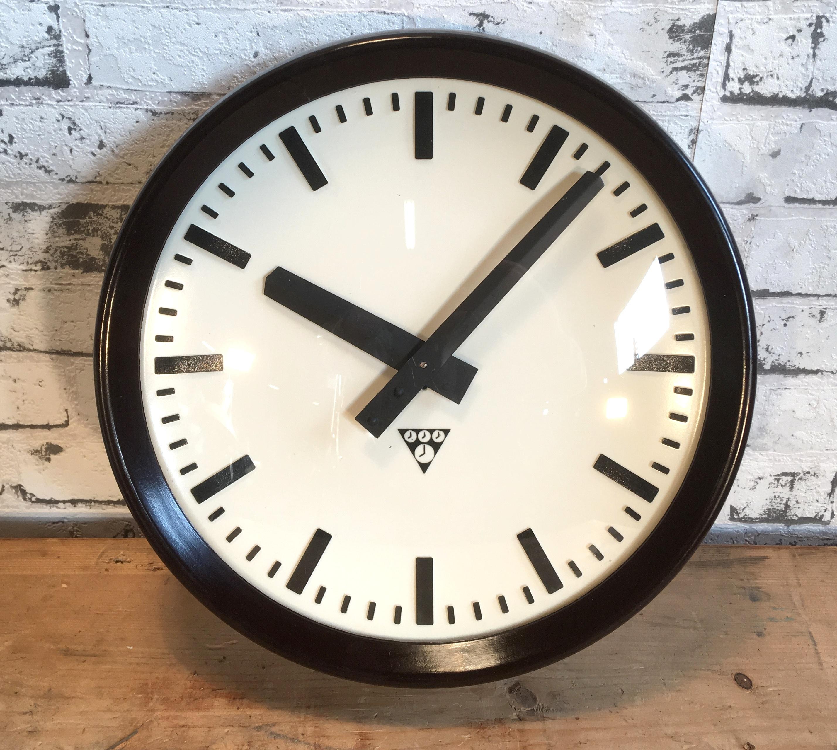 This wall clock was produced by Pragotron in former Czechoslovakia during the 1960s. The piece features a brown bakelite frame, white bakelite dial, aluminium hands and a curved clear glass cover. The piece has been converted into a battery-powered