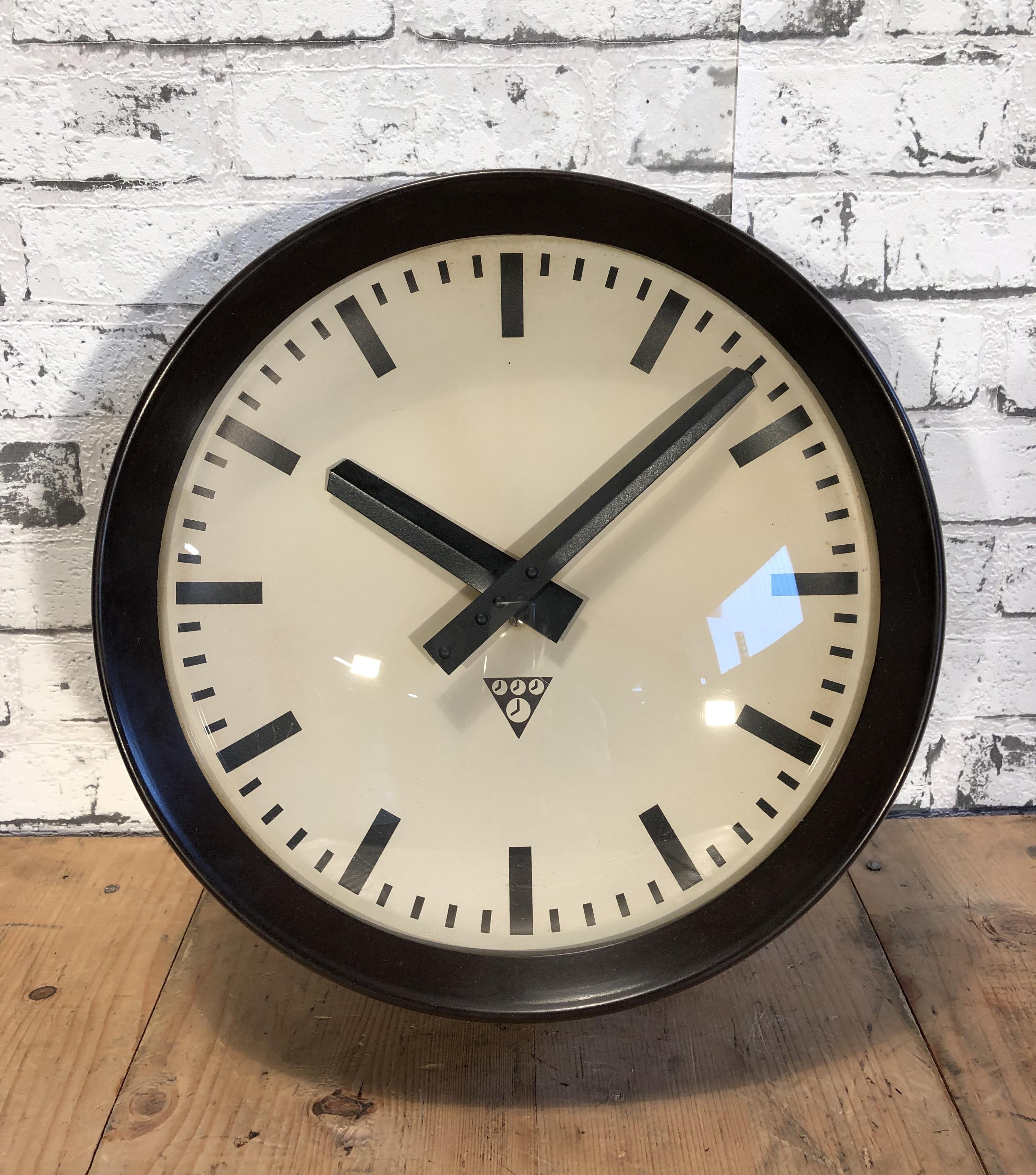 This wall clock was produced by Pragotron in former Czechoslovakia during the 1960s. The piece features a brown Bakelite frame, aluminium dial and a curved clear glass cover. The piece has been converted into a battery-powered clockwork and requires