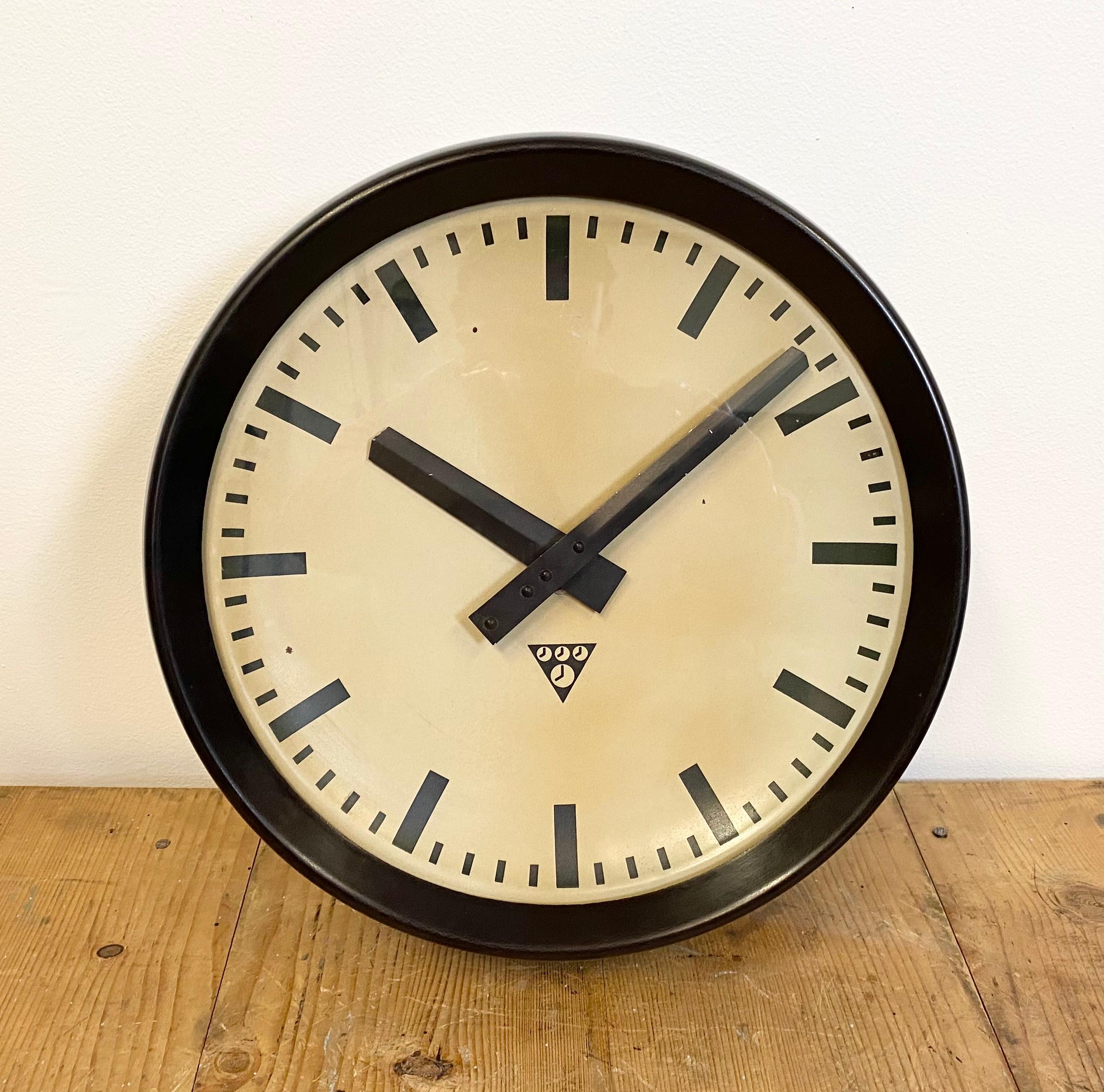 This wall clock was produced by Pragotron in former Czechoslovakia during the 1960s. The piece features a brown bakelite frame, aluminium dial and a clear glass cover. The piece has been converted into a battery-powered clockwork and requires only