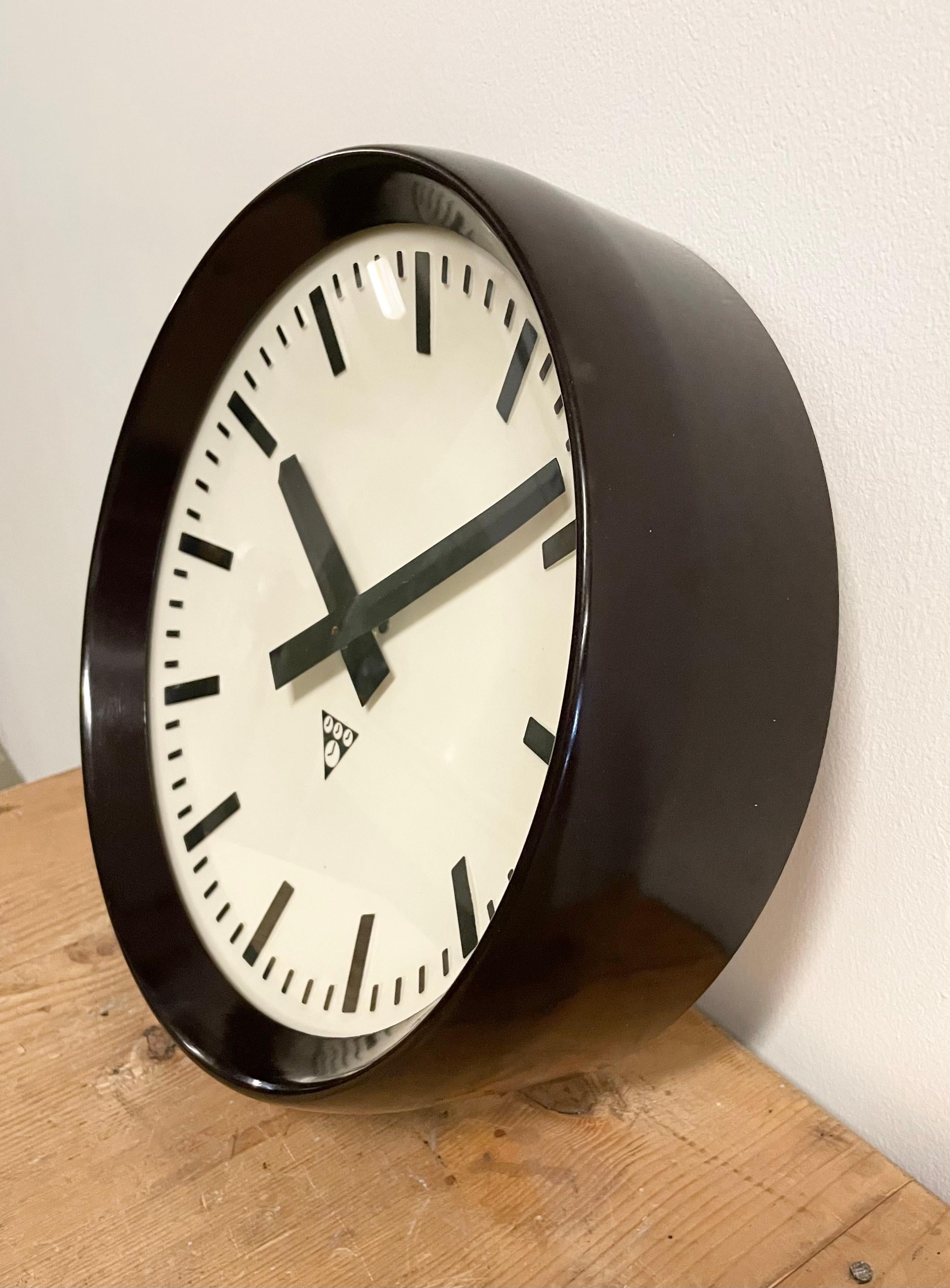 This wall clock was produced by Pragotron in former Czechoslovakia during the 1960s. The piece features a brown bakelite frame, white bakelite dial, aluminum hands and a curved clear glass cover. The piece has been converted into a battery-powered