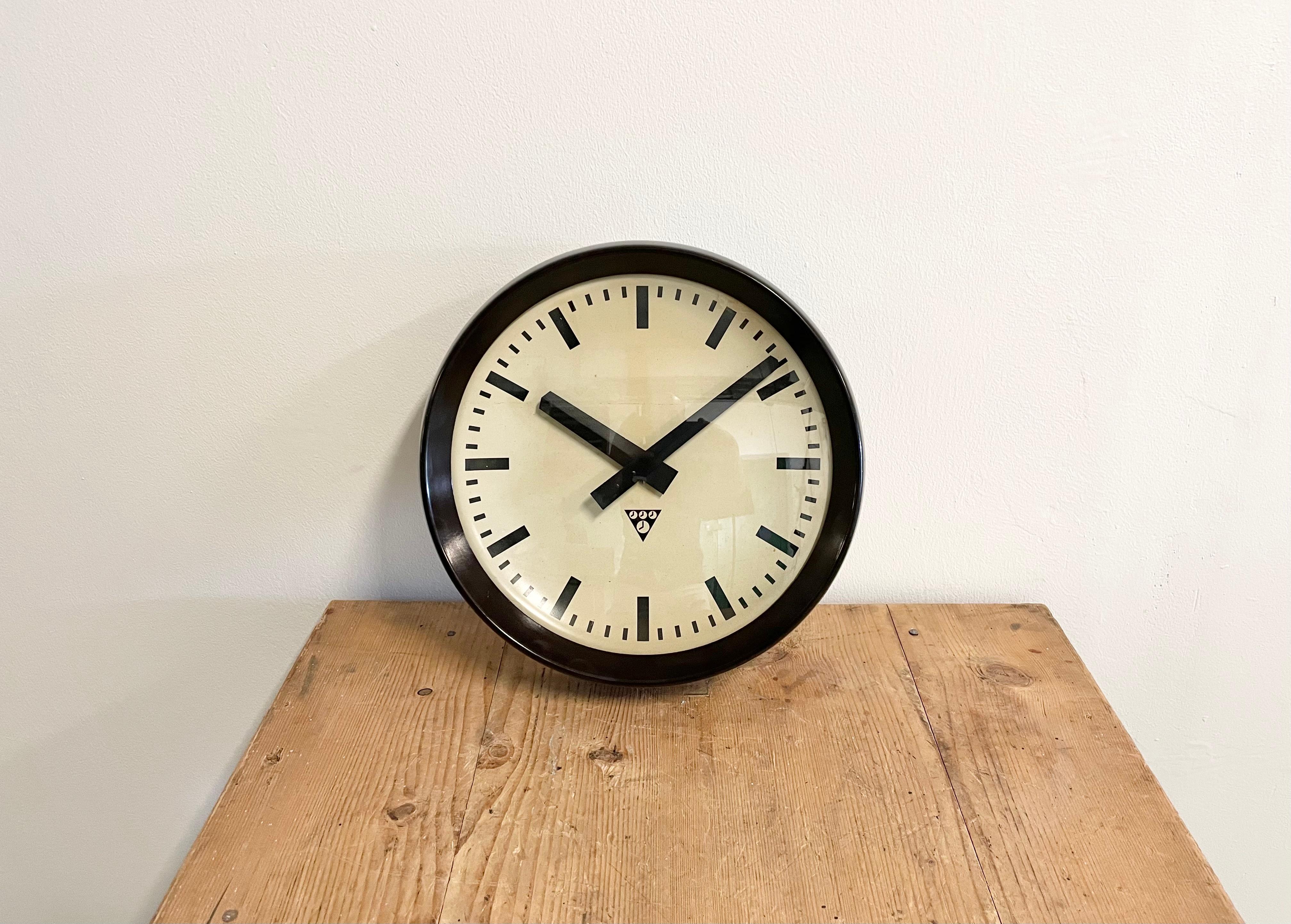 This wall clock was produced by Pragotron in former Czechoslovakia during the 1960s. The piece features a brown bakelite frame, aluminium dial and a clear glass cover. The piece has been converted into a battery-powered clockwork and requires only