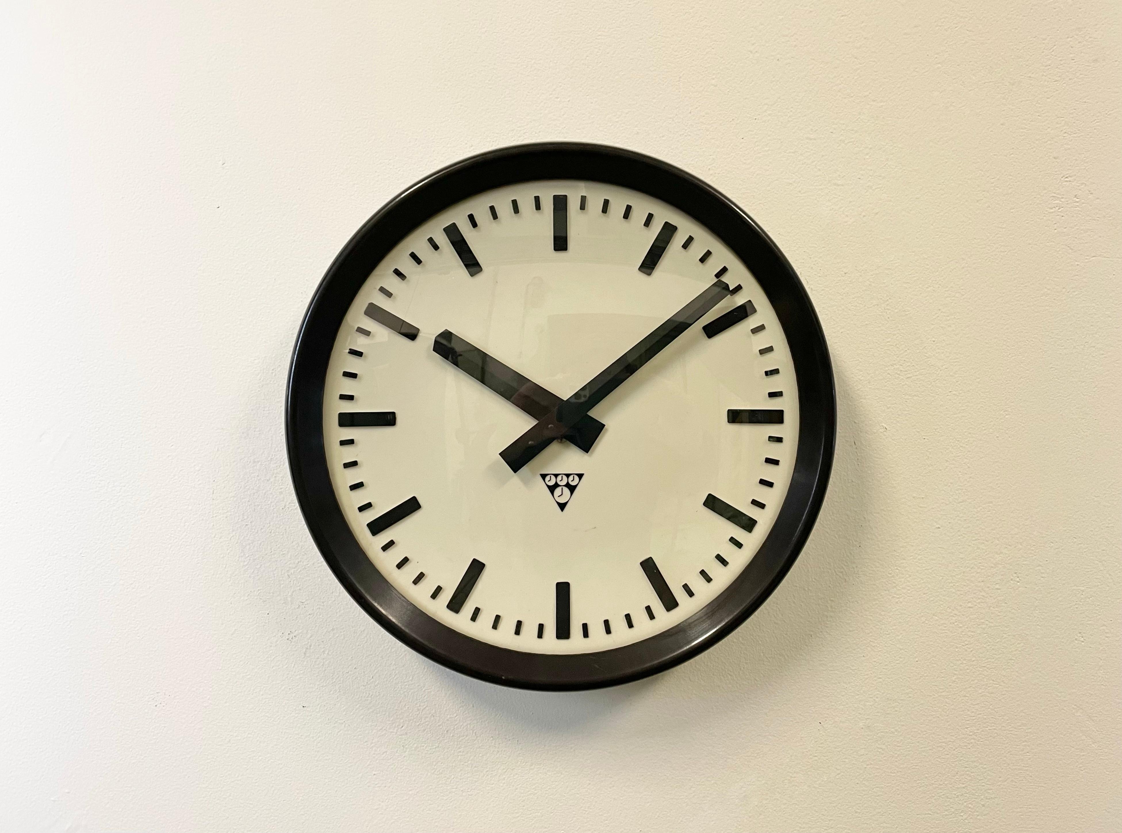 Wall clock produced by Pragotron in former Czechoslovakia during the 1960s. It features a brown bakelite frame, a white bakelite dial, an aluminium hands and a curved clear glass cover. The piece has been converted into a battery-powered clockwork