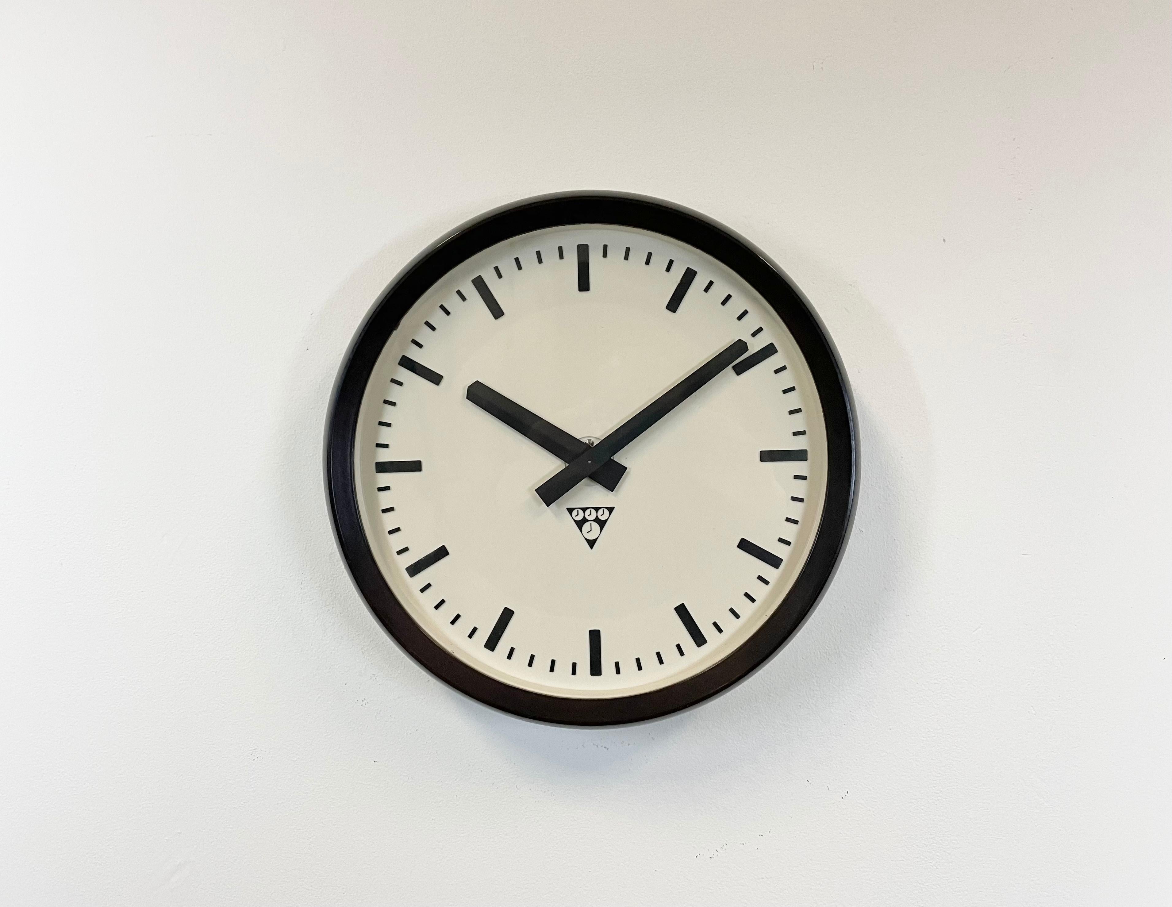 This wall clock was produced by Pragotron in former Czechoslovakia during the 1960s. The piece features a brown bakelite frame, a white bakelite dial, an aluminum hands and a clear glass cover. The piece has been converted into a battery-powered