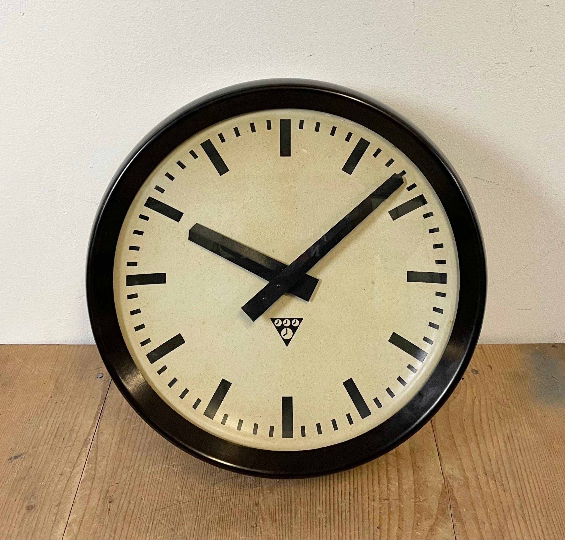 This wall clock was produced by Pragotron in former Czechoslovakia during the 1960s. The piece features a brown bakelite frame, aluminium dial and a convex clear glass cover. The piece has been converted into a battery-powered clockwork and requires