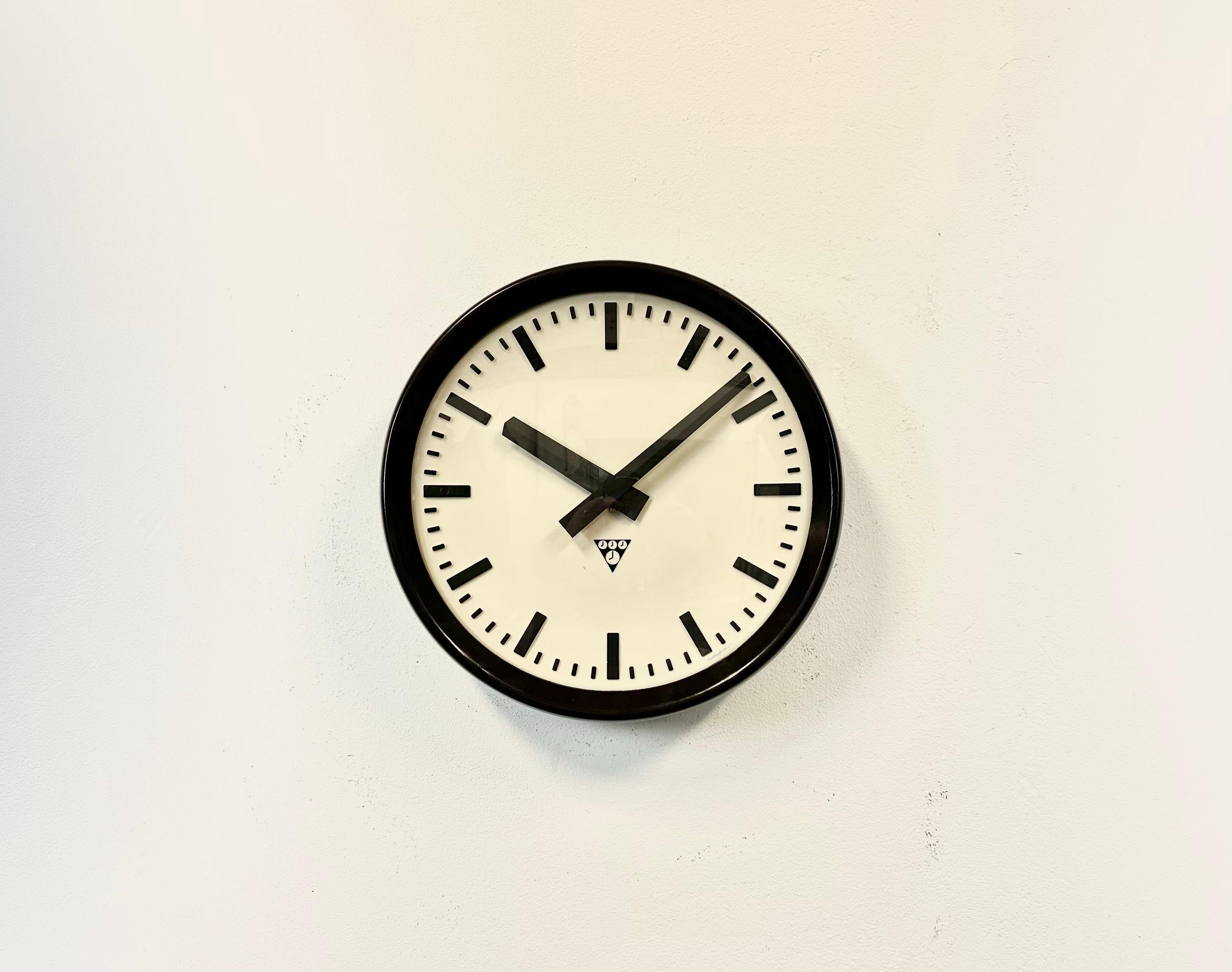 This wall clock was produced by Pragotron in former Czechoslovakia during the 1960s. It features a brown bakelite frame, a white bakelite dial, an aluminium hands, a clear glass cover and brown bakelite back.The piece has been converted into a