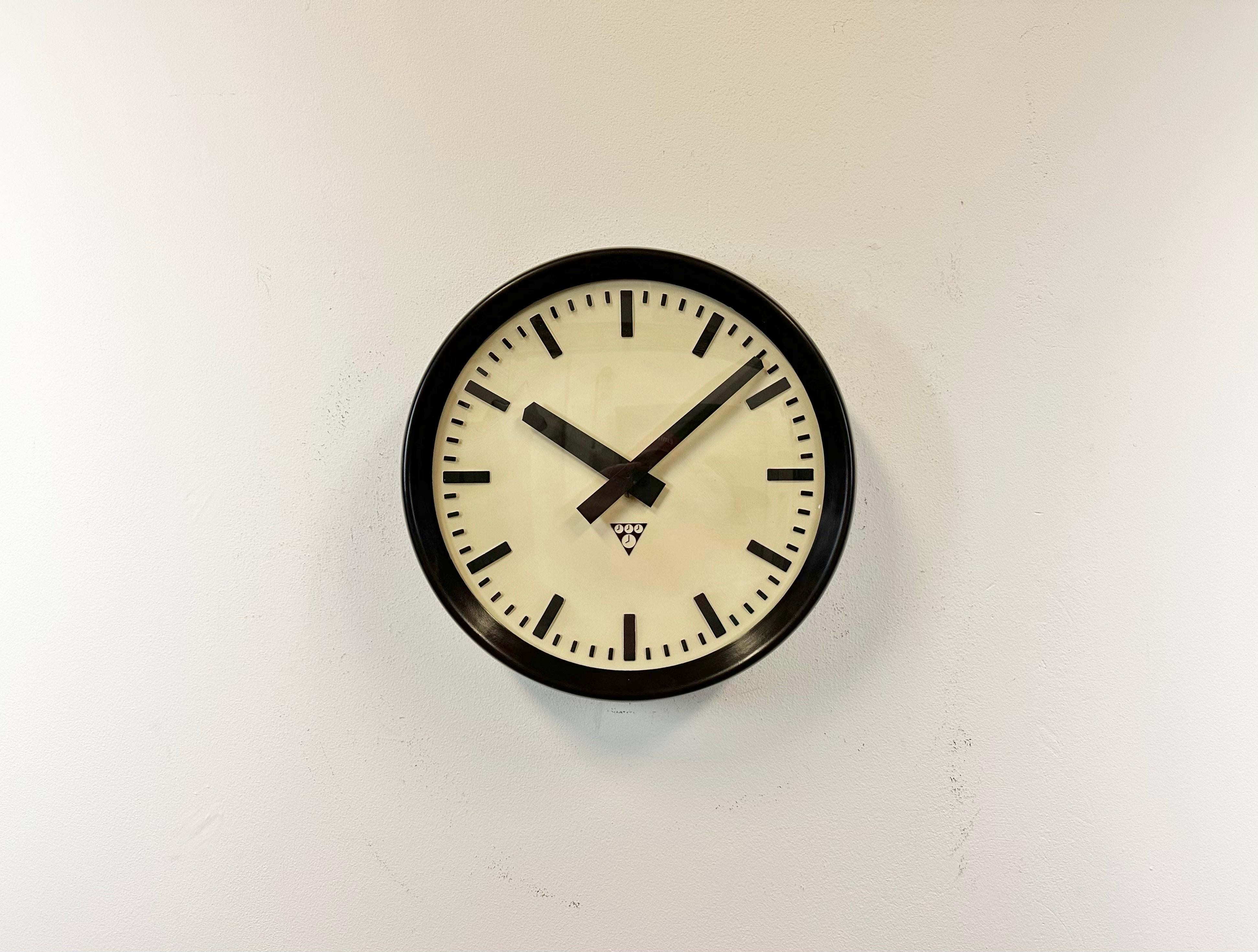 Wall clock produced by Pragotron in former Czechoslovakia during the 1960s. It features a brown bakelite frame, a plastic dial, an aluminium hands and a convex clear glass cover. The piece has been converted into a battery-powered clockwork and