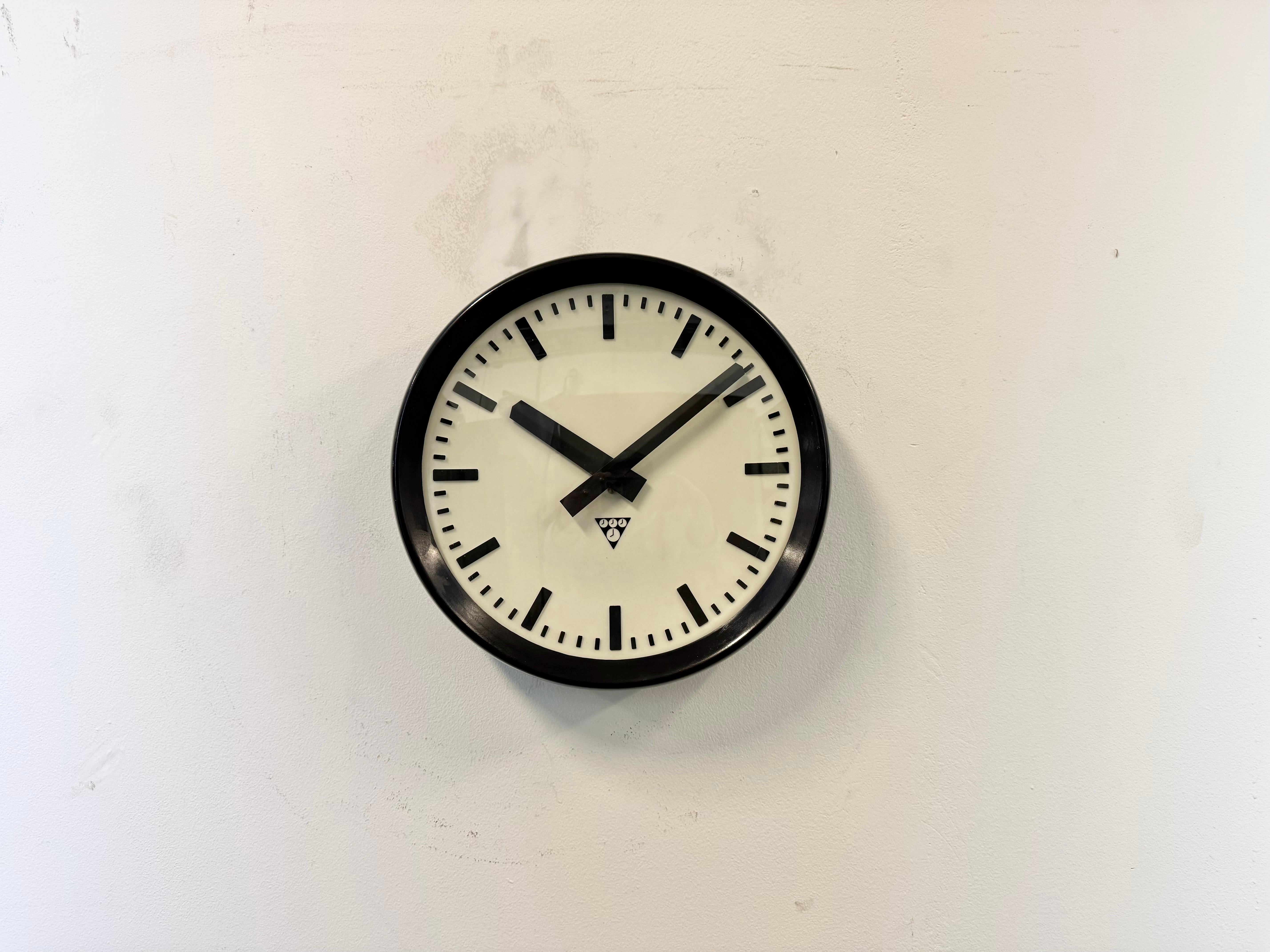 Cette horloge murale a été produite par Pragotron dans l'ancienne Tchécoslovaquie au cours des années 1960. Elle présente une monture en bakélite brune, un cadran en plastique, des aiguilles en aluminium et un cadran en acier.  Couvercle en verre