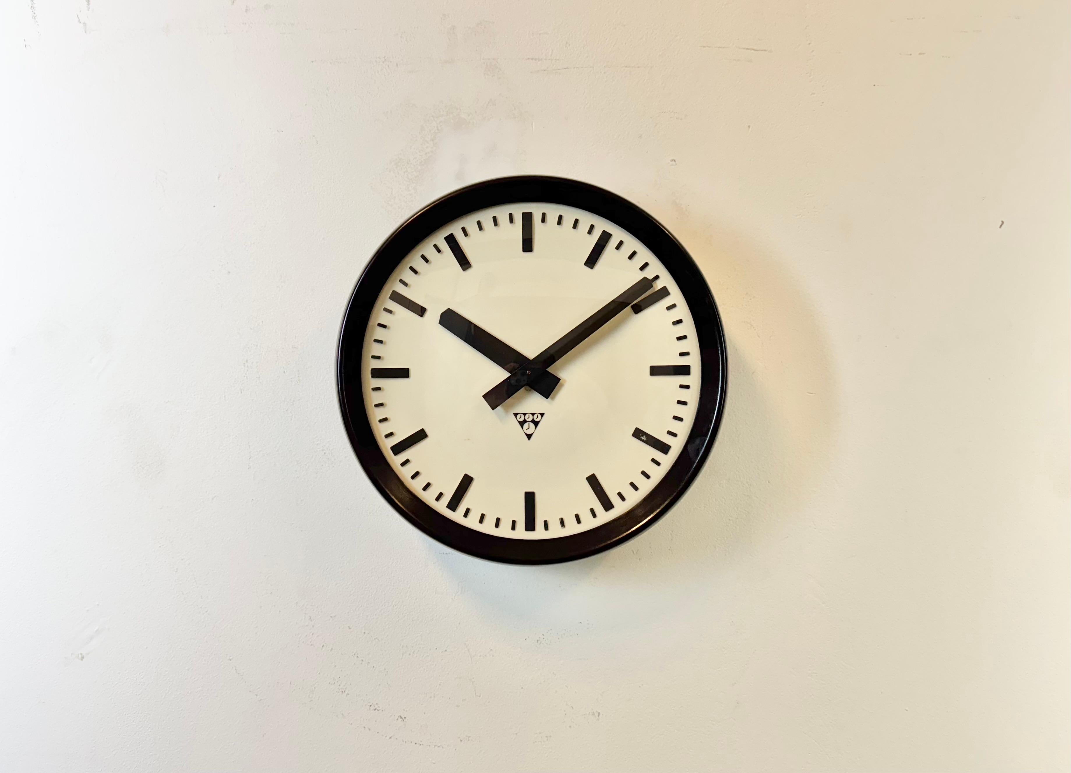 This wall clock was produced by Pragotron in former Czechoslovakia during the 1960s. It features a brown bakelite frame and back, a plastic dial, an aluminium hands and a  convex clear glass cover. The piece has been converted into a battery-powered