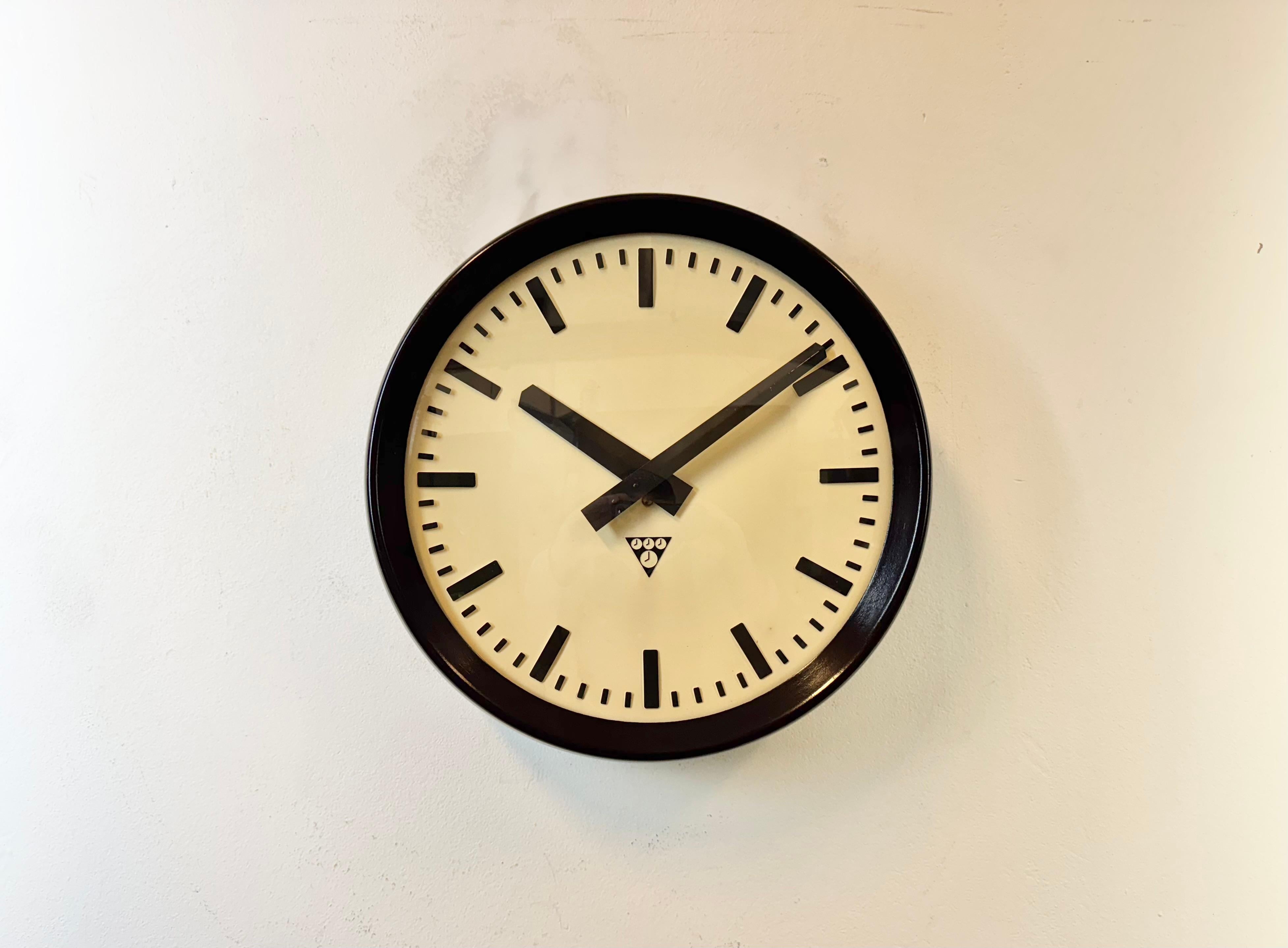 This wall clock was produced by Pragotron in former Czechoslovakia during the 1960s. It features a brown bakelite frame, a plastic dial, an aluminium hands and a  convex clear glass cover. The piece has been converted into a battery-powered