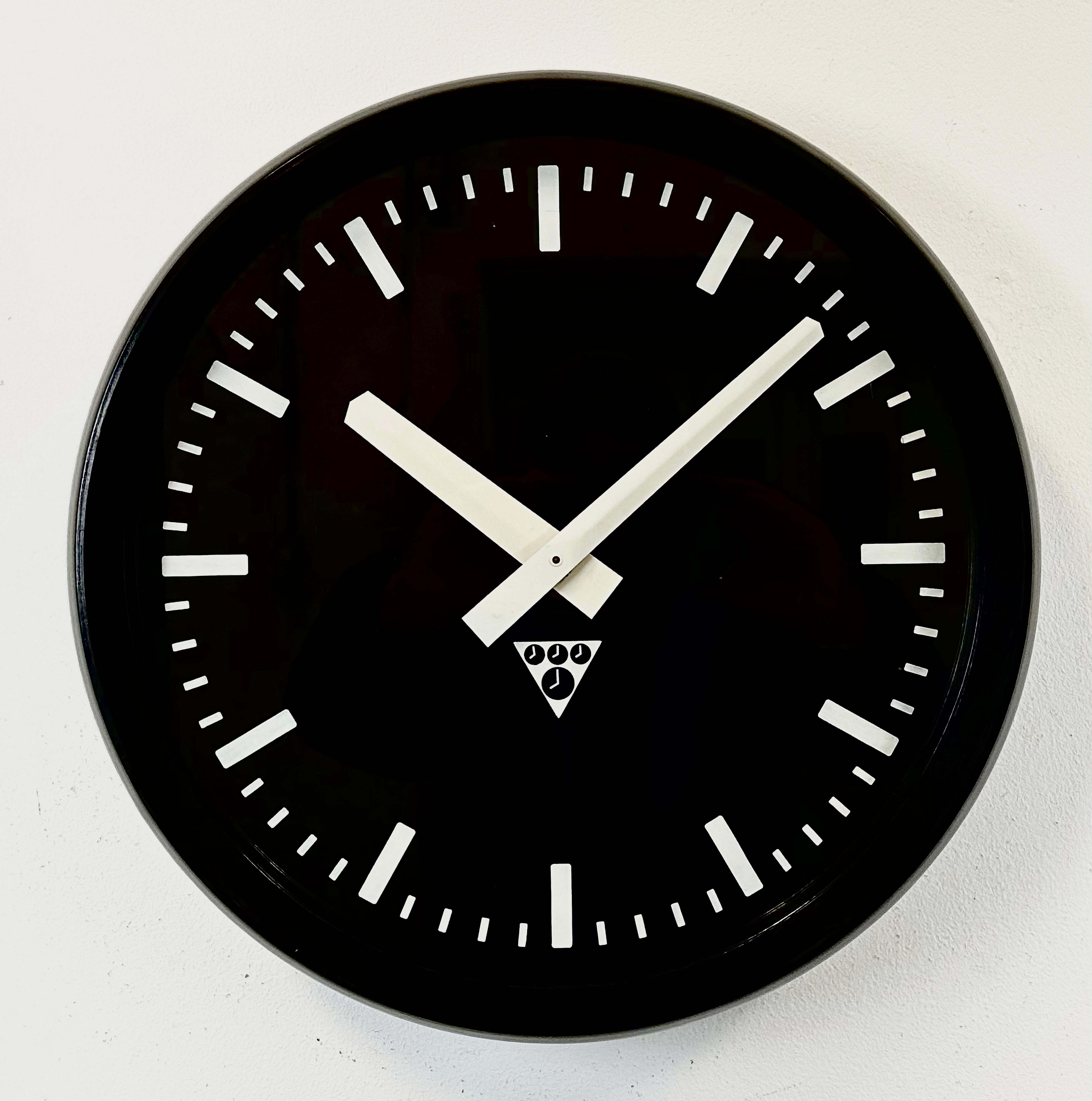 This wall clock was produced by Pragotron in former Czechoslovakia during the 1970s. The piece features a brown bakelite frame, a black bakelite dial, an aluminum hands and a clear glass cover. The piece has been converted into a battery-powered