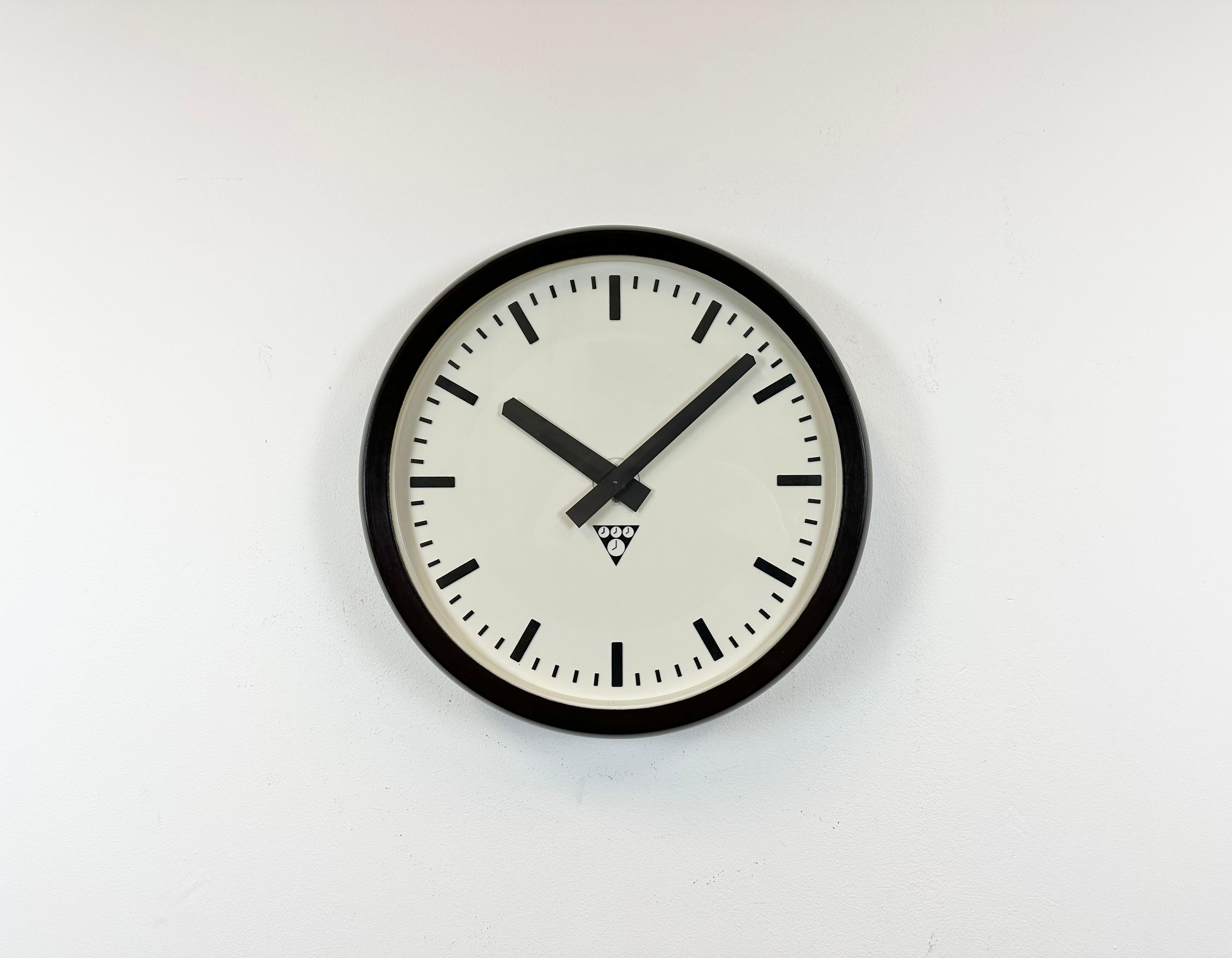 Diese Wanduhr wurde von Pragotron in der ehemaligen Tschechoslowakei in den 1970er Jahren hergestellt. Die Uhr hat einen Rahmen aus braunem Bakelit, ein weißes Bakelit-Zifferblatt, Aluminiumzeiger und eine Abdeckung aus Klarglas. Das Stück wurde in