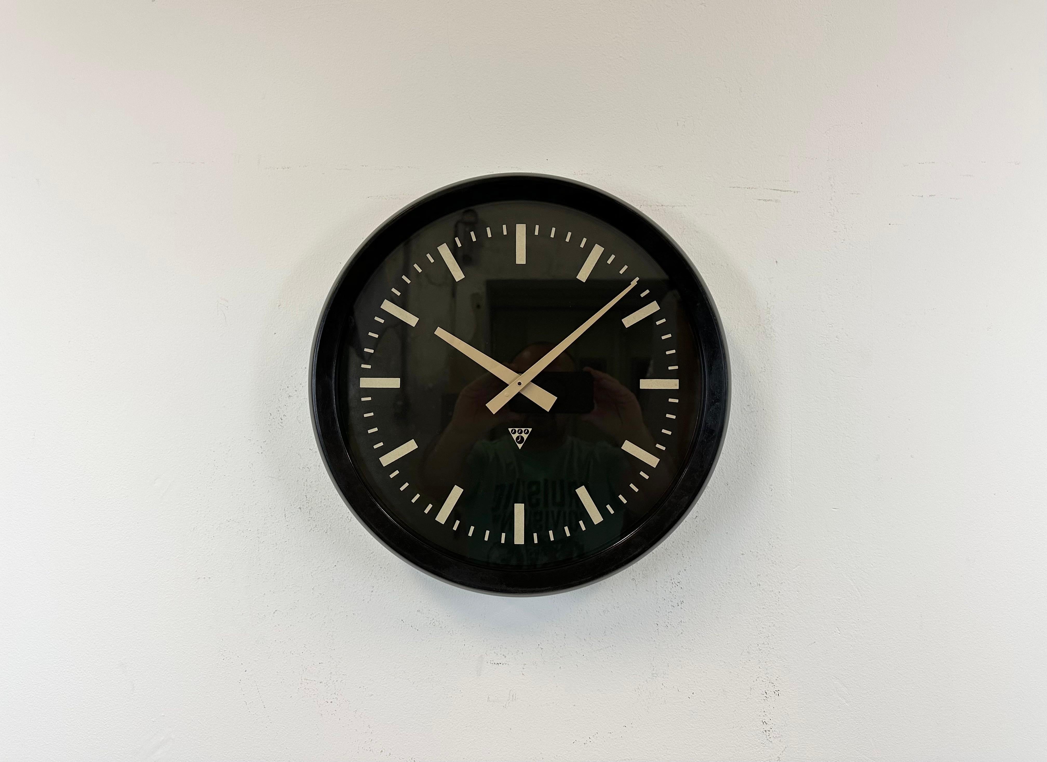 This wall clock was produced by Pragotron in former Czechoslovakia during the 1970s. The piece features a dark brown (black) bakelite frame, a black bakelite dial, an aluminum hands and a clear glass cover. The piece has been converted into a