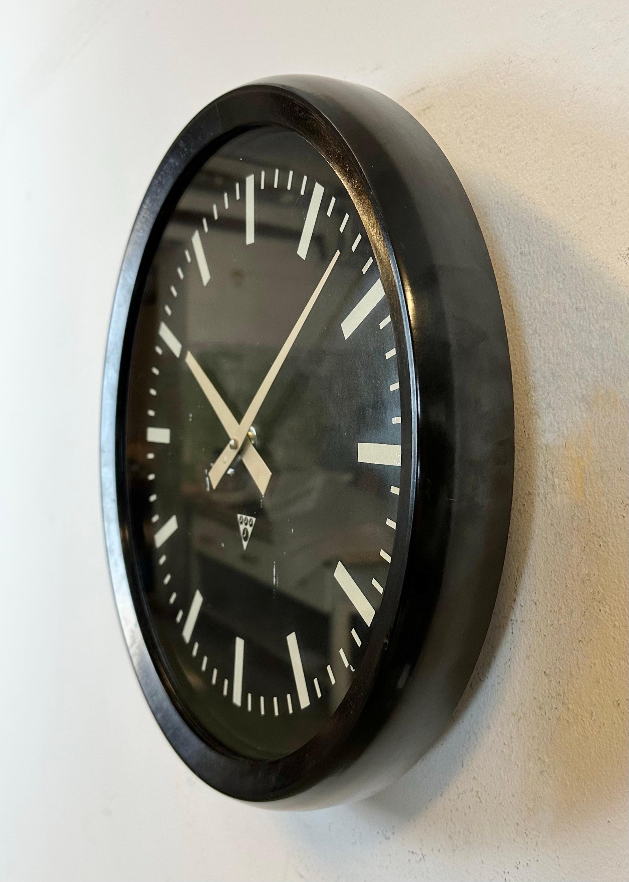 This wall clock was produced by Pragotron in former Czechoslovakia during the 1970s. The piece features a dark brown (black) bakelite frame, a black bakelite dial, an aluminum hands and a clear glass cover. The piece has been converted into a