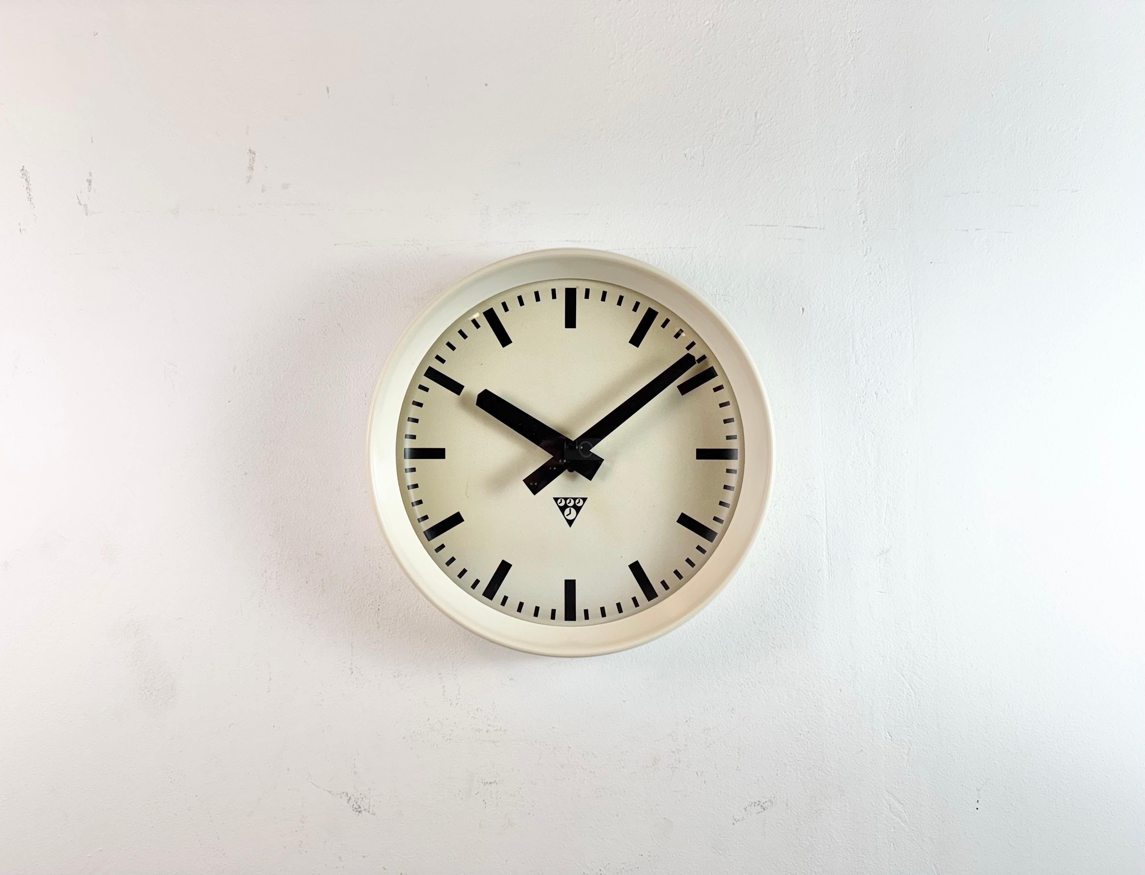 Diese Wanduhr wurde von Pragotron in der ehemaligen Tschechoslowakei in den 1960er Jahren hergestellt. Sie hat einen beigen Bakelitrahmen, ein Aluminiumzifferblatt, Zeiger und eine gewölbte Klarglasabdeckung. Das Stück wurde in ein