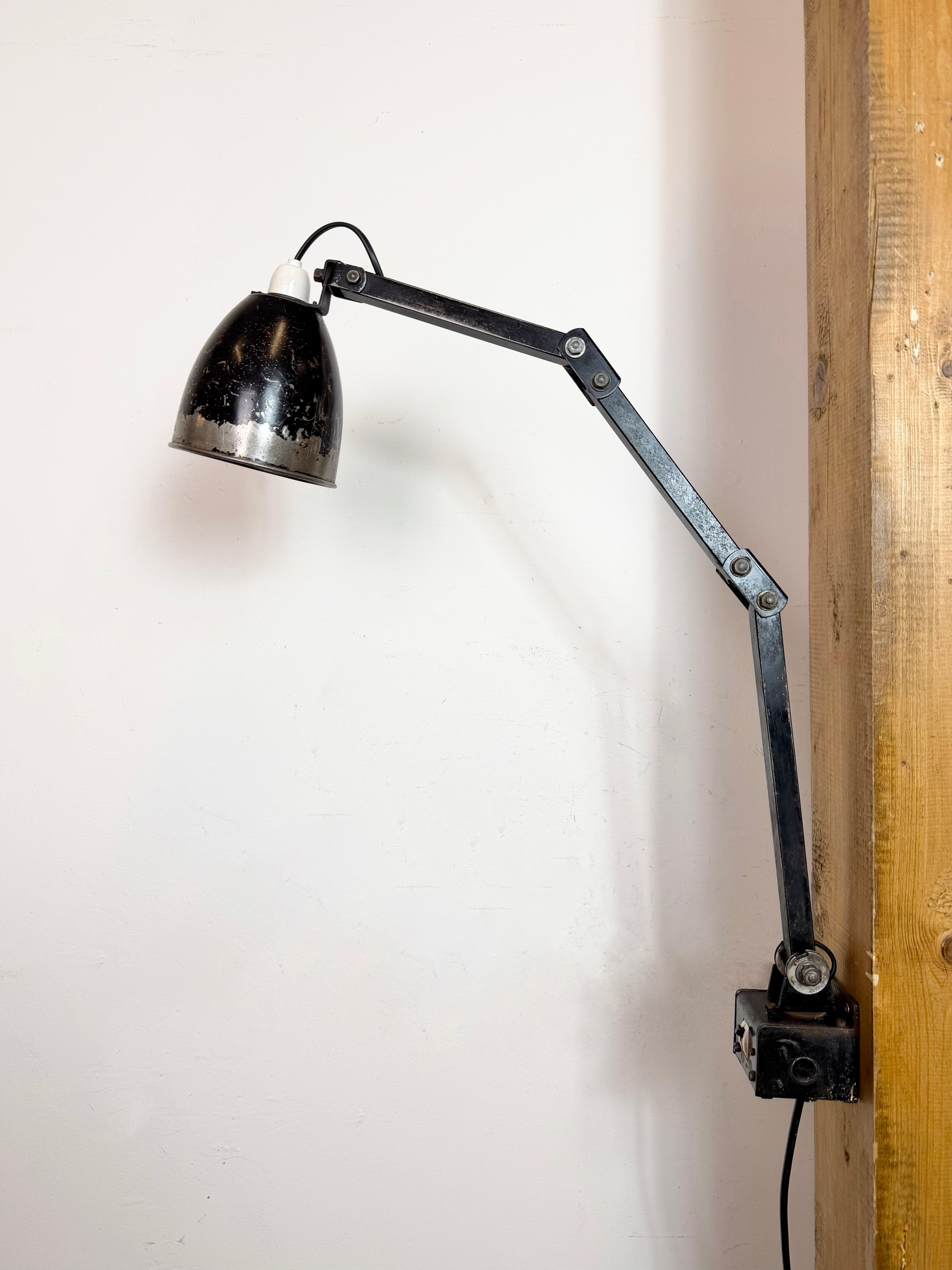 This vintage Industrial adjustable wall lamp was produced by Memlite in United Kingdom during the 1960s. The lamp has a metal shade.The iron arm has four adjustable joints and can be turned sideways. The original switch is situated on the wall