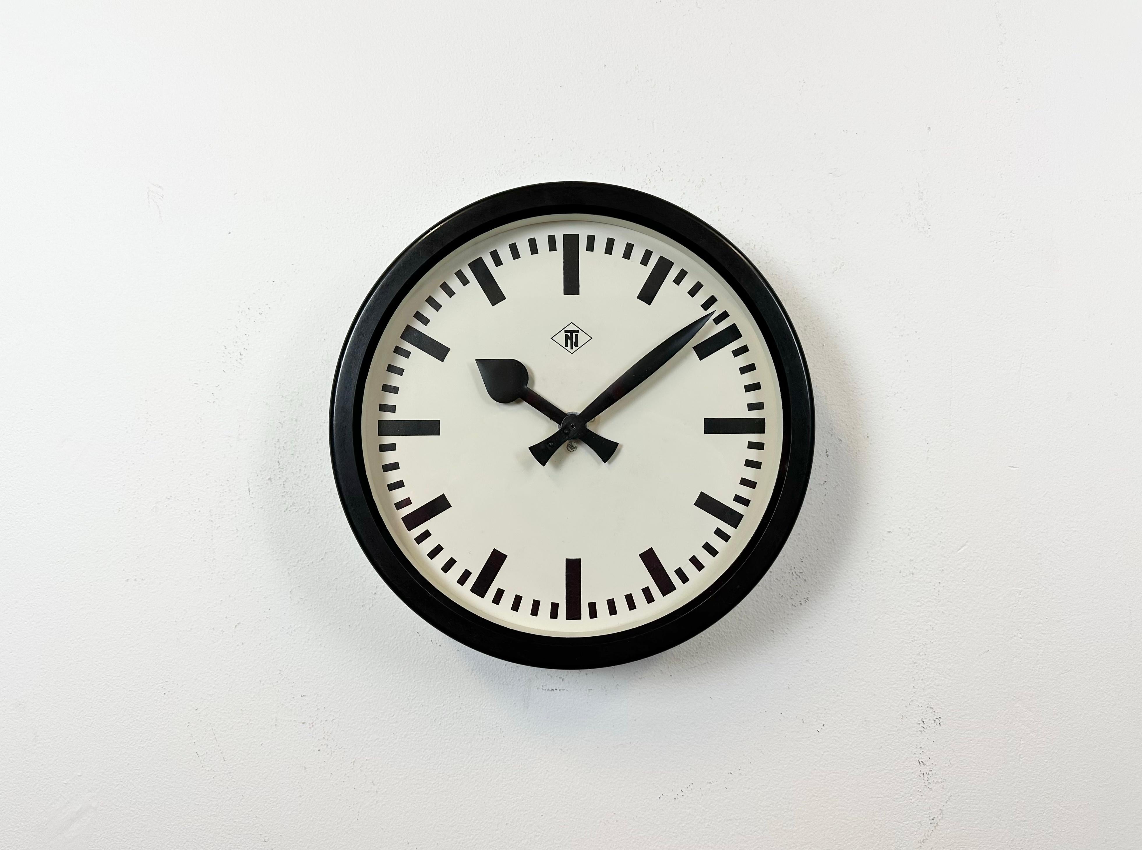 This wall clock was produced by TN Telefonbau und Normalzeit in Germany during the 1940s. It features a black bakelitel frame, a metal dial and a clear glass cover. The piece has been converted into a battery-powered clockwork and requires only one