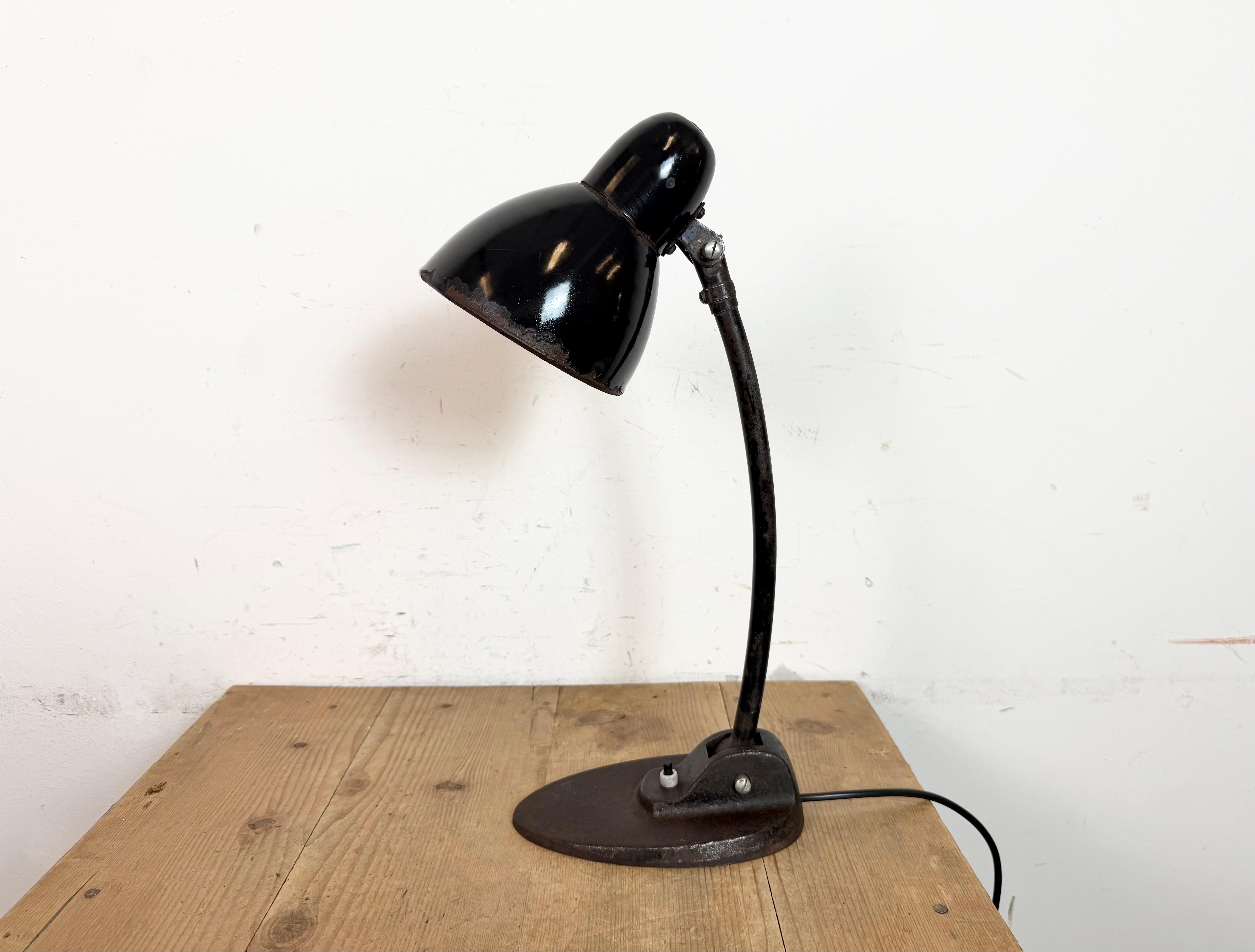 Industrial table lamp made in Bauuhaus era in Germany during the 1930s. It features a black enamel shade with white enamel interior, a cast iron base with original switch and an arm with two adjustable joints. Original socket requires E27/ E26