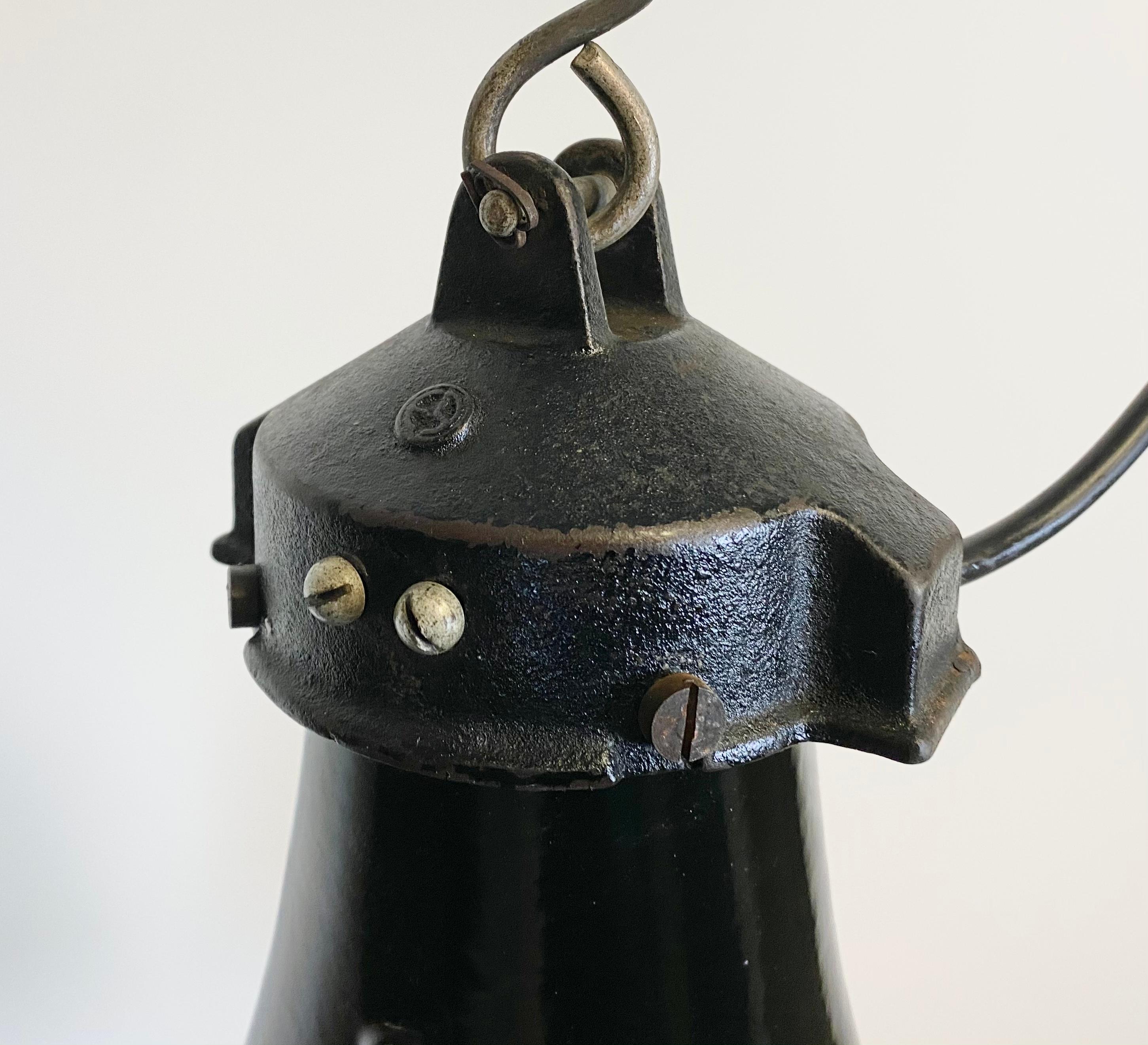 Lampe suspendue vintage industrielle en émail noir dans le style Bauhaus. Utilisé dans les usines de l'ancienne Tchécoslovaquie dans les années 1930. Intérieur en émail blanc. Dessus en fonte. Nouveau câblage et nouvelle douille en porcelaine pour