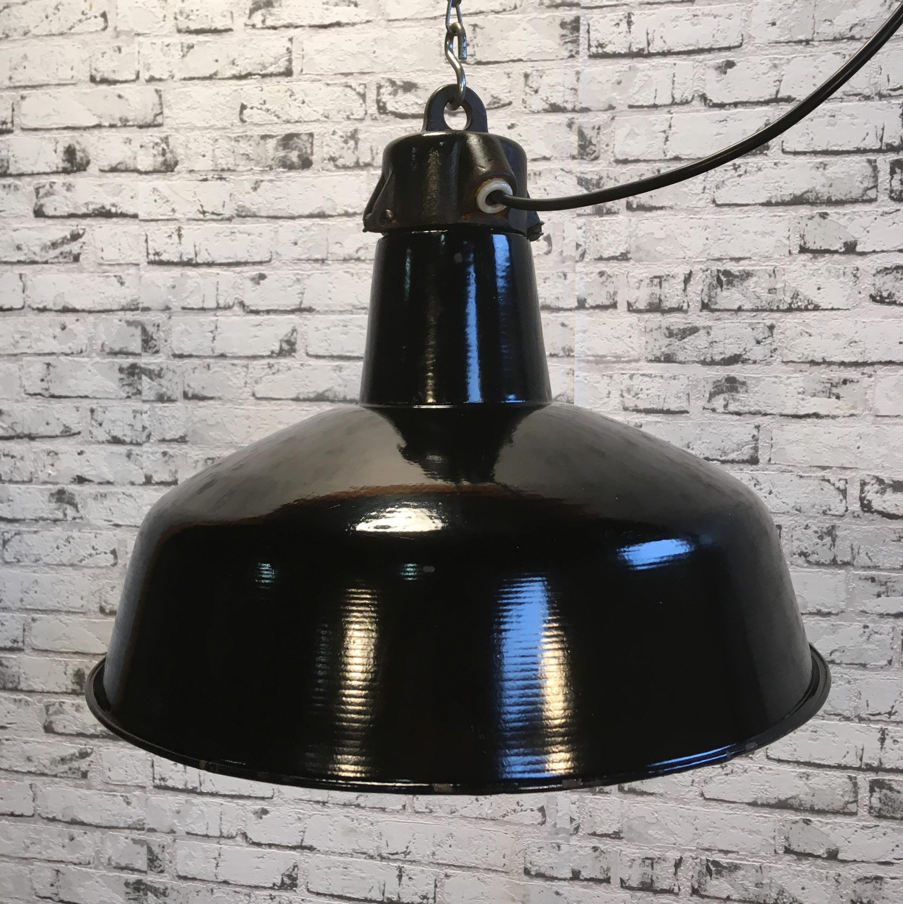 Industrial hanging lamp manufactured during the 1950s in former Czechoslovakia. Black enamel shade, white enamel interior. Cast iron top.
New porcelain socket for E 27 lightbulbs and wire. Very good vintage condition. Fully functional.
