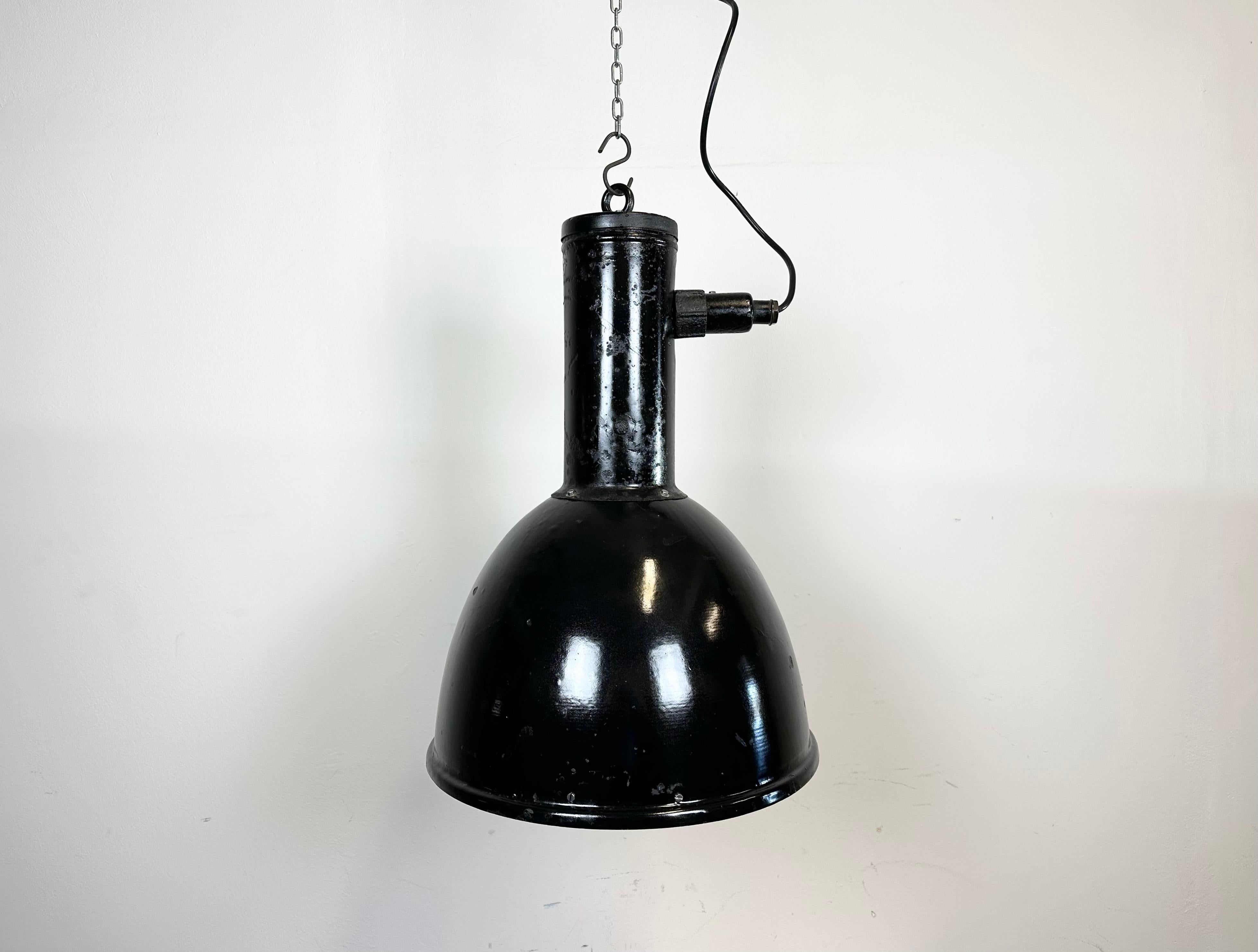 Industrial factory pendant light made in former Czechoslovakia during the 1950s. It features black enamel shade with white enamel interior and black lacquered iron neck with hook. The porcelain socket requires stndard E 27/ E26 light bulbs. New