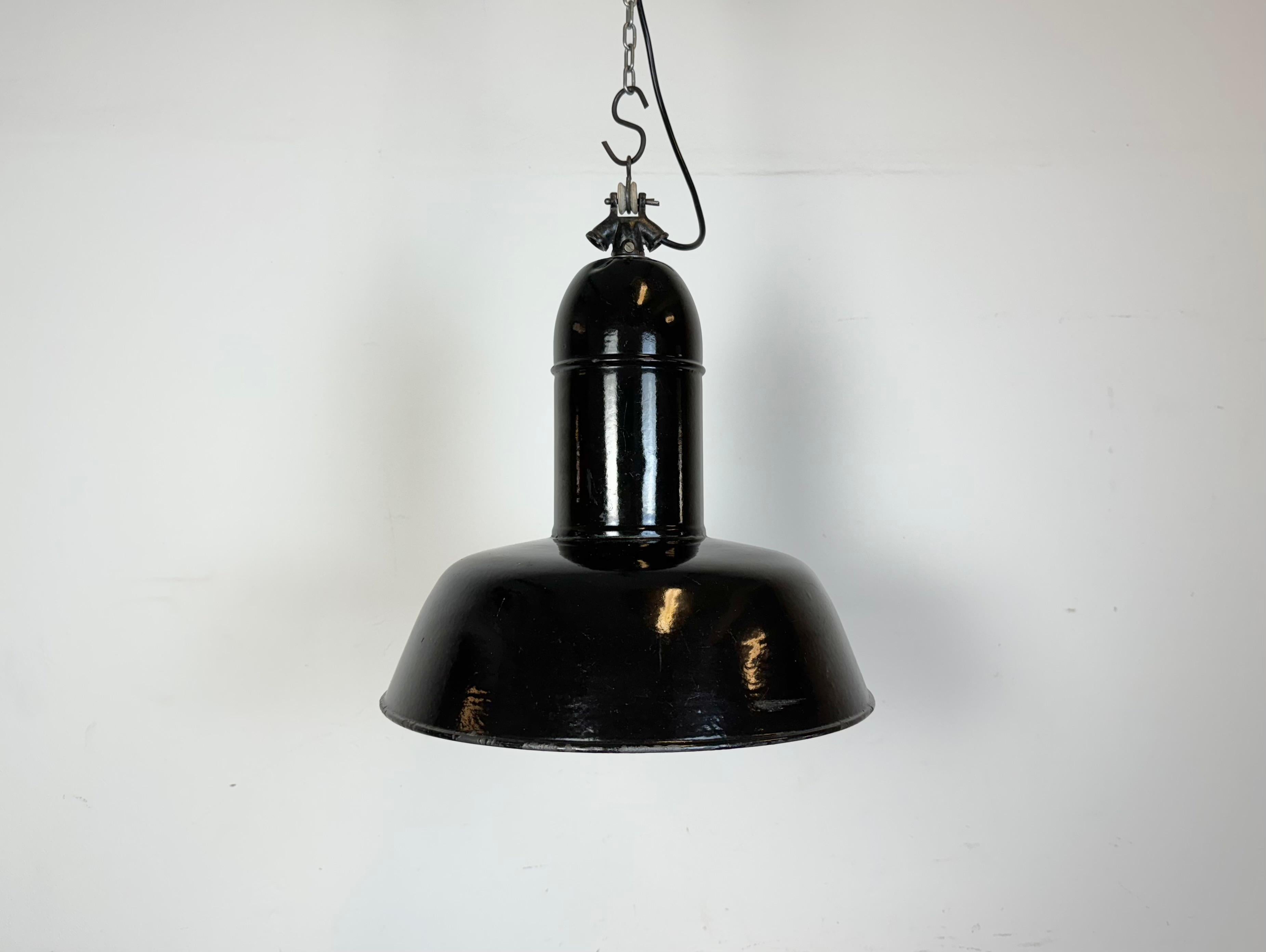 Industrial black enamel pendant light made in Germany during the 1930s. White enamel inside the shade. Cast iron top. The porcelain socket requires standard E 27/ E26 light bulbs. New wire. Fully functional. The weight of the lamp is 2 kg.
