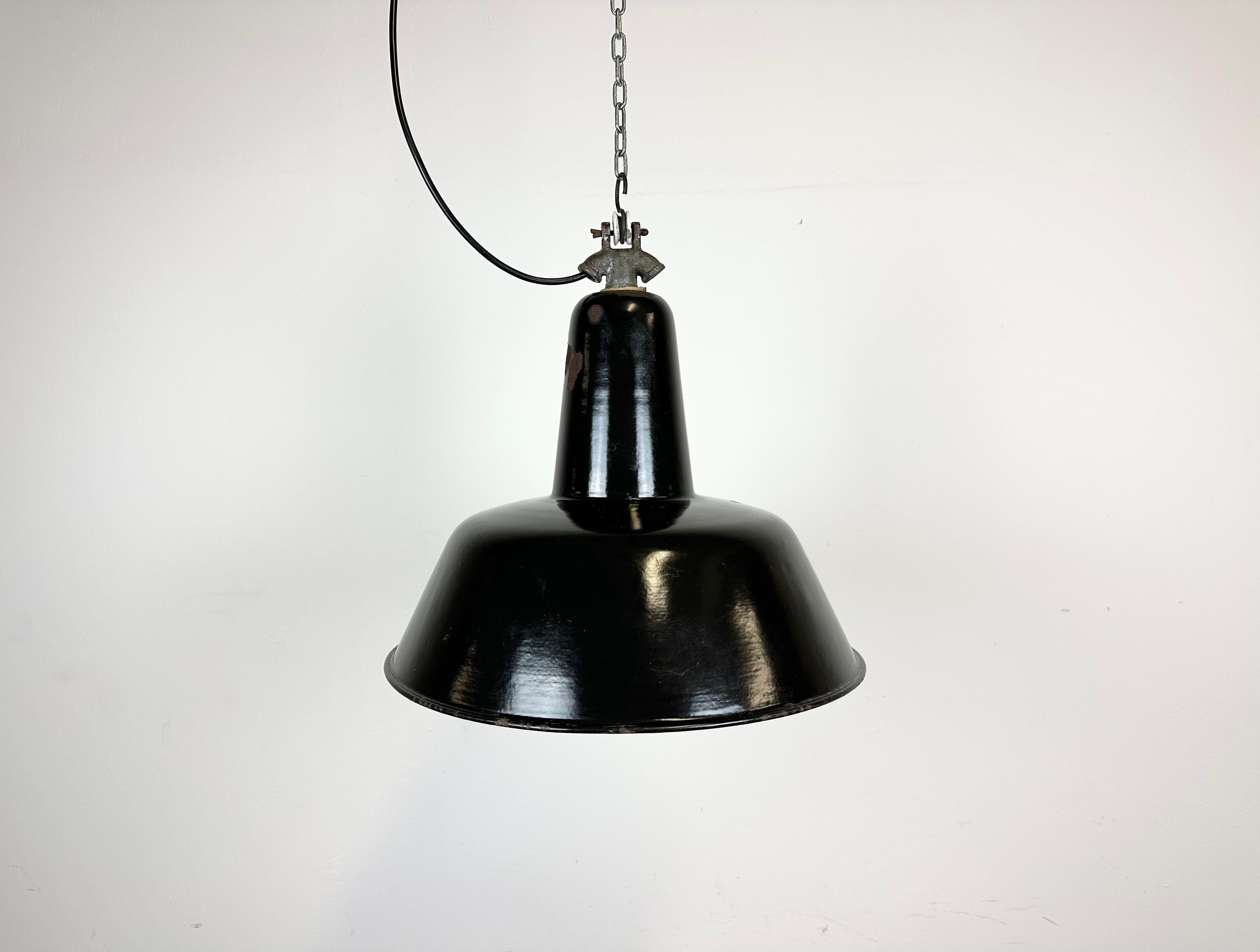 Industrial black enamel pendant light made in former Czechoslovakia during the 1950s. White enamel inside the shade. Cast iron top. The porcelain socket requires E 27/ E26 light bulbs. New wire. Fully functional. The weight of the lamp is 1 .4kg.