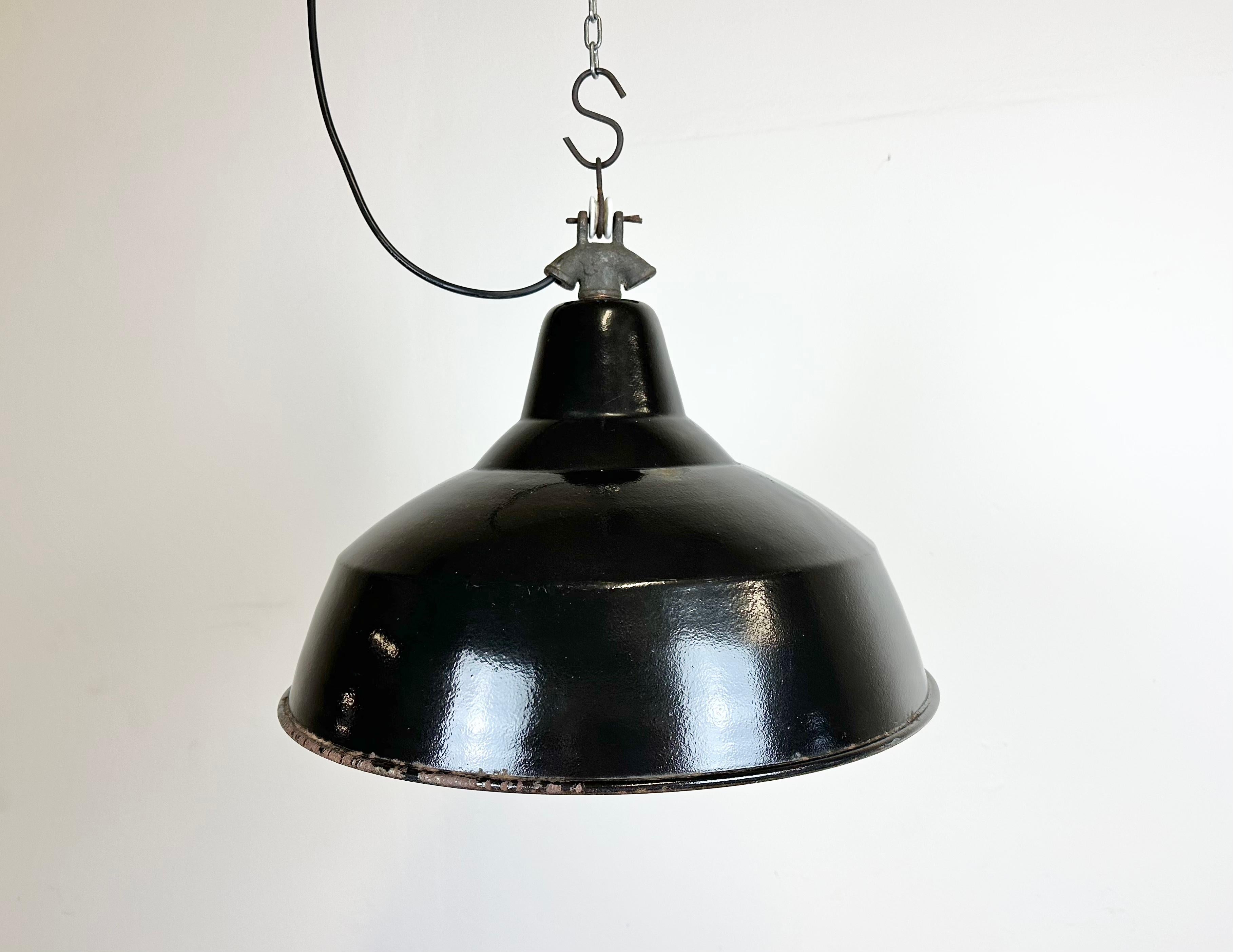 Industrial black enamel pendant light made in former Czechoslovakia during the 1950s. White enamel inside the shade. Cast iron top. The porcelain socket requires E 27/ E26 light bulbs. New wire. Fully functional. The weight of the lamp is 1.8 kg.