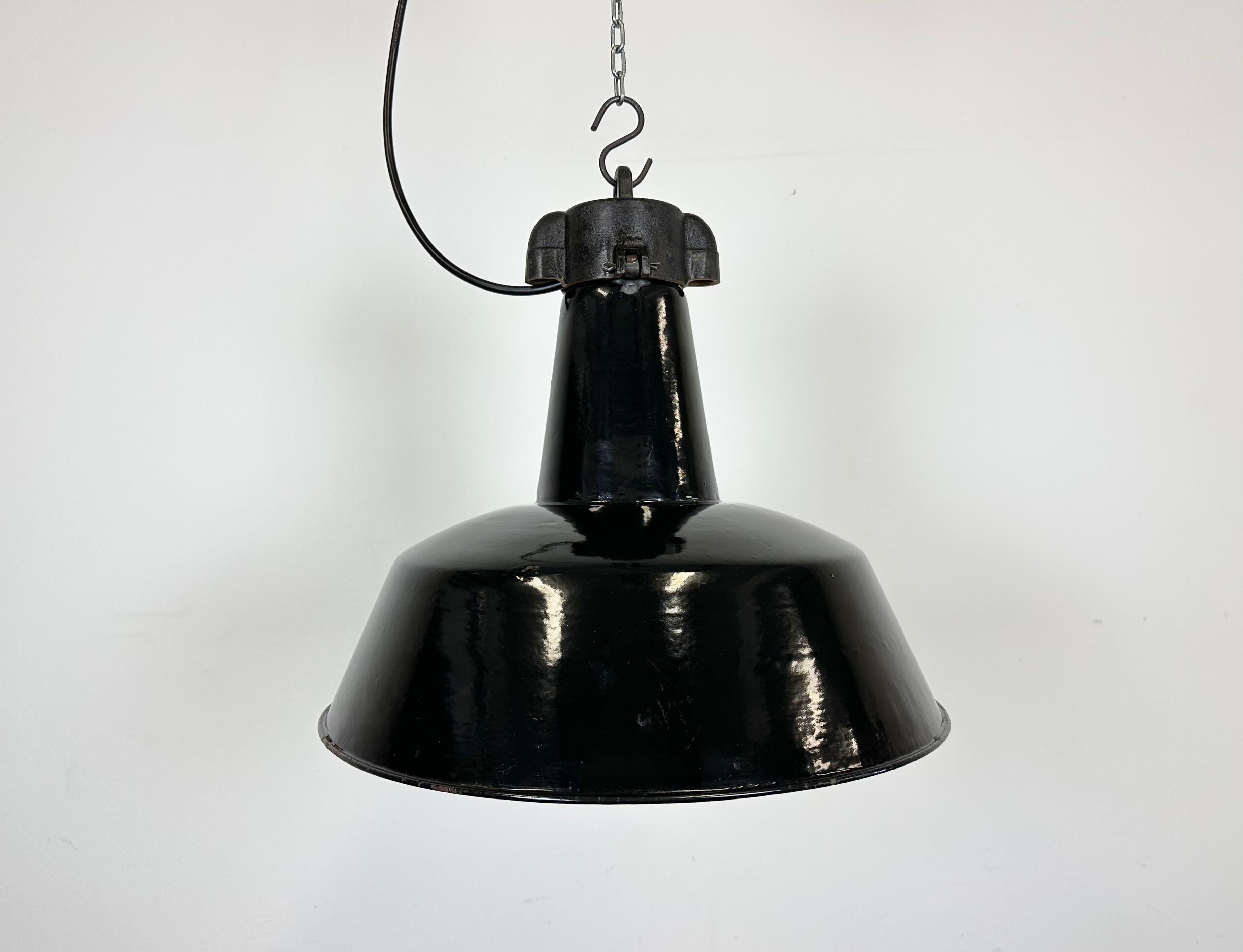 Industrial black enamel pendant light made by Elektrosvit in former Czechoslovakia during the 1950s. White enamel inside the shade. Cast iron top. The porcelain socket requires E 27/ E26 light bulbs. New wire. Fully functional. The weight of the