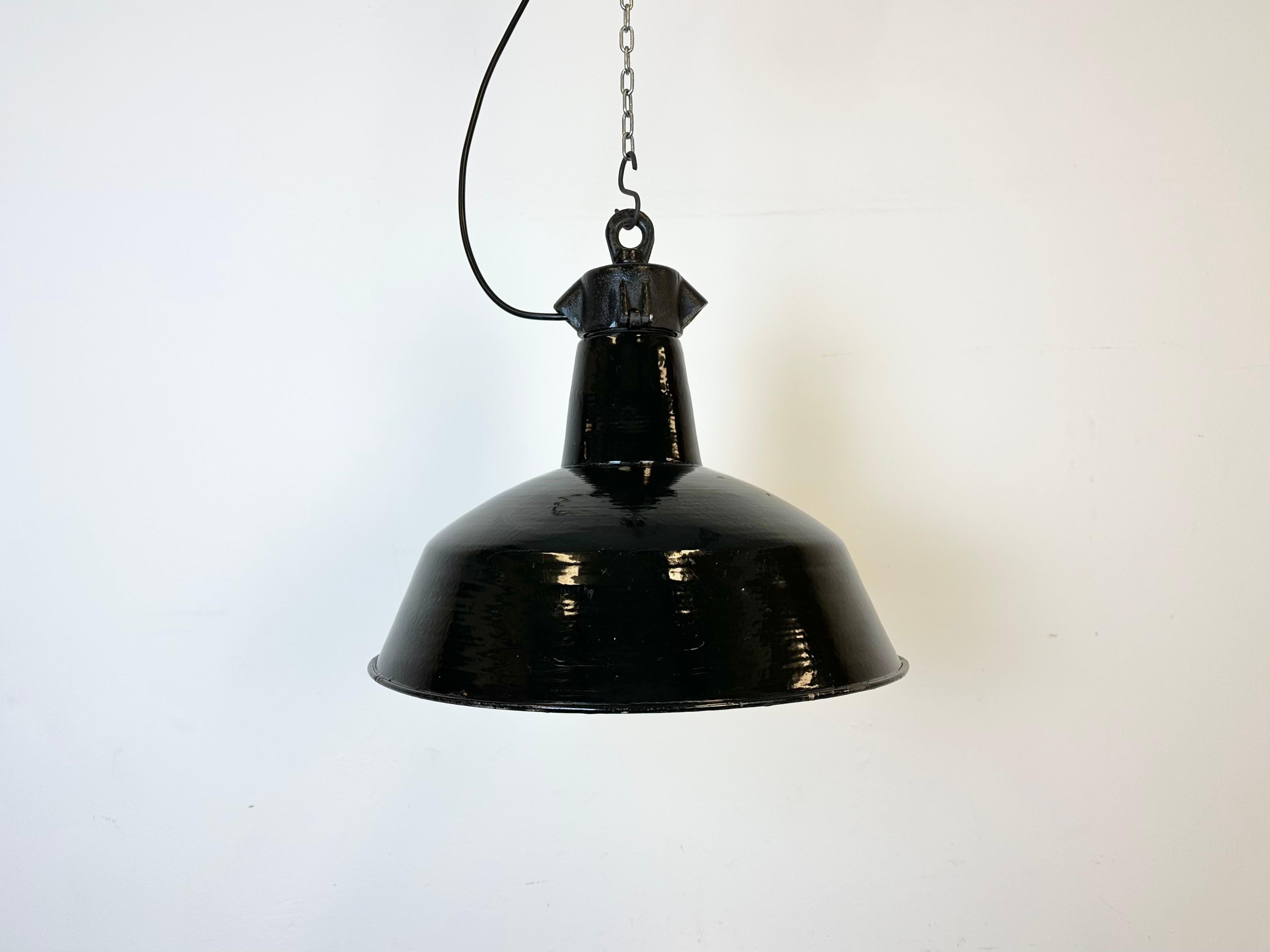 Industrial black enamel pendant light made by Elektrosvit in former Czechoslovakia during the 1950s. White enamel inside the shade. Cast iron top. The porcelain socket requires E 27/ E26 light bulbs. New wire. Fully functional. The weight of the