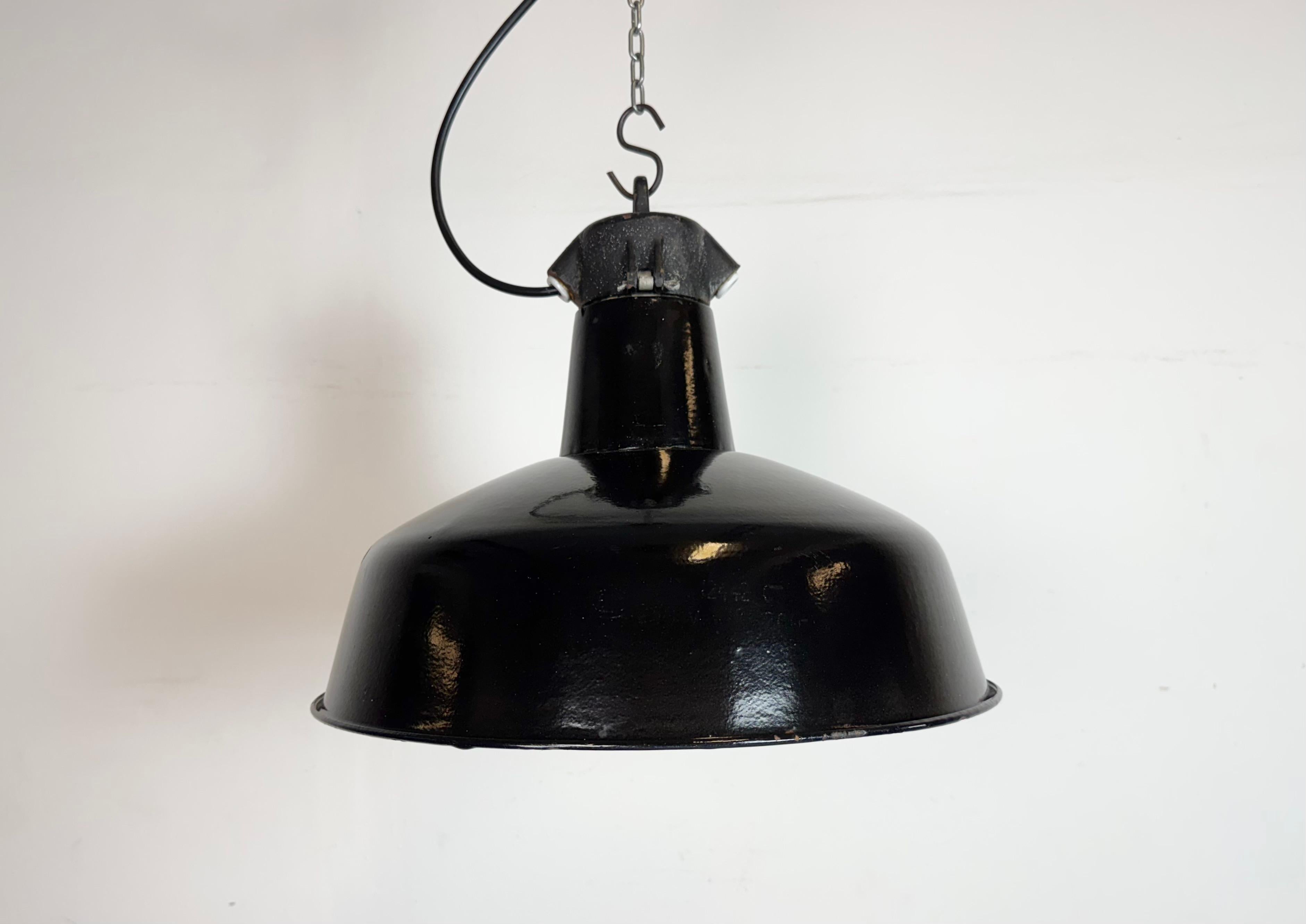 Industrielle Pendelleuchte aus schwarzer Emaille, hergestellt von Elektrosvit in der ehemaligen Tschechoslowakei in den 1950er Jahren. Weiße Emaille im Inneren des Schirms. Platte aus Gusseisen. Die Porzellanfassung ist für handelsübliche Glühbirnen