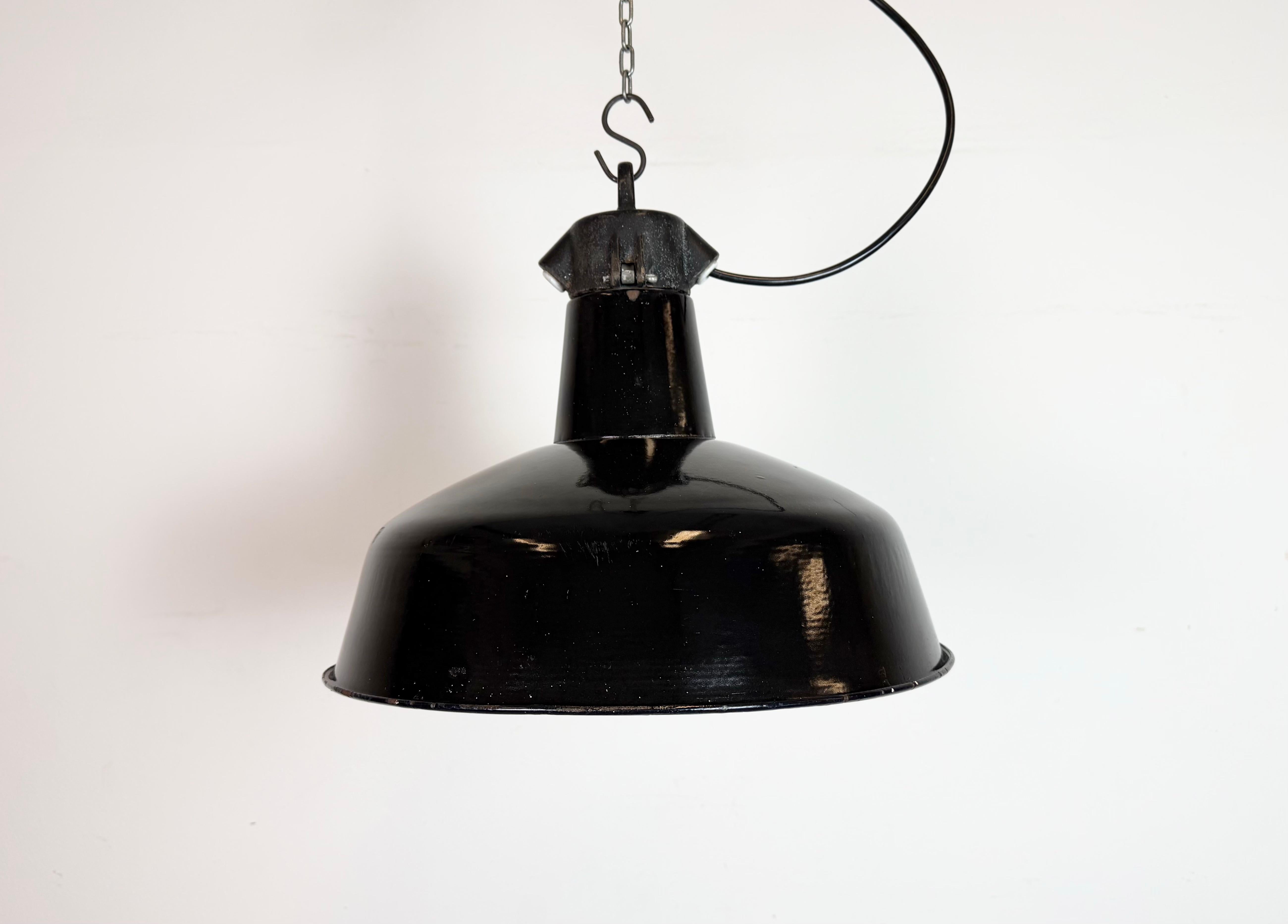 Suspension industrielle en émail noir fabriquée par Elektrosvit dans l'ancienne Tchécoslovaquie au cours des années 1950. Émail blanc à l'intérieur de la teinte. Dessus en fonte. La douille en porcelaine est compatible avec les ampoules standard E
