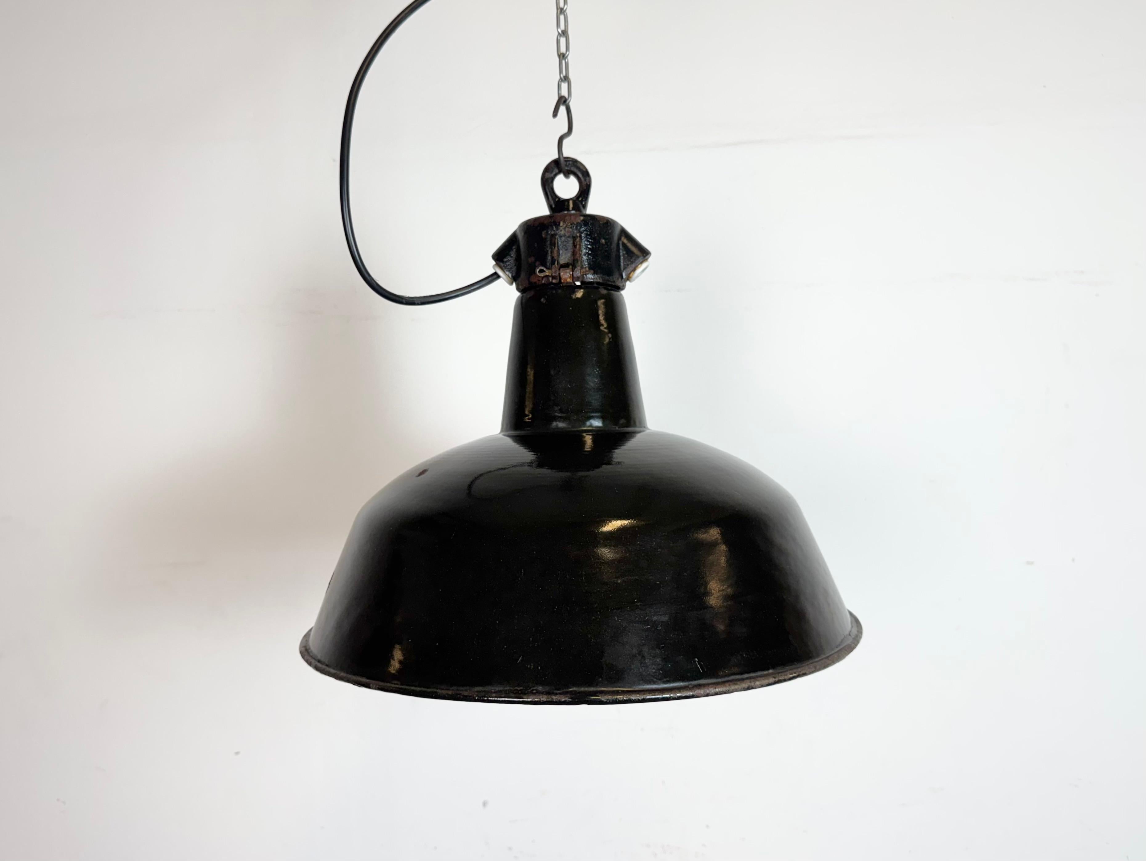 Lampada a sospensione industriale in smalto nero realizzata da Elektrosvit nell'ex Cecoslovacchia negli anni Cinquanta. Smalto bianco all'interno del paralume. Piano in ghisa. L'attacco in porcellana richiede lampadine E 27/ E26. Un nuovo cavo.