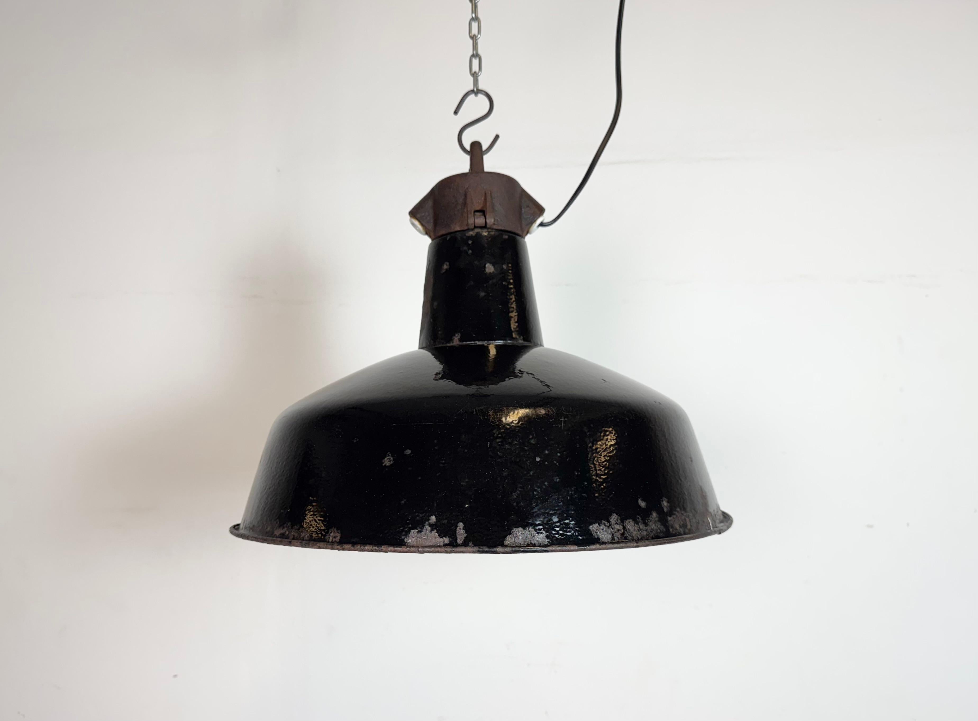 Industrielle Pendelleuchte aus schwarzer Emaille, hergestellt von Elektrosvit in der ehemaligen Tschechoslowakei in den 1950er Jahren. Weiße Emaille im Inneren des Schirms. Platte aus Gusseisen. Die Porzellanfassung ist für handelsübliche Glühbirnen