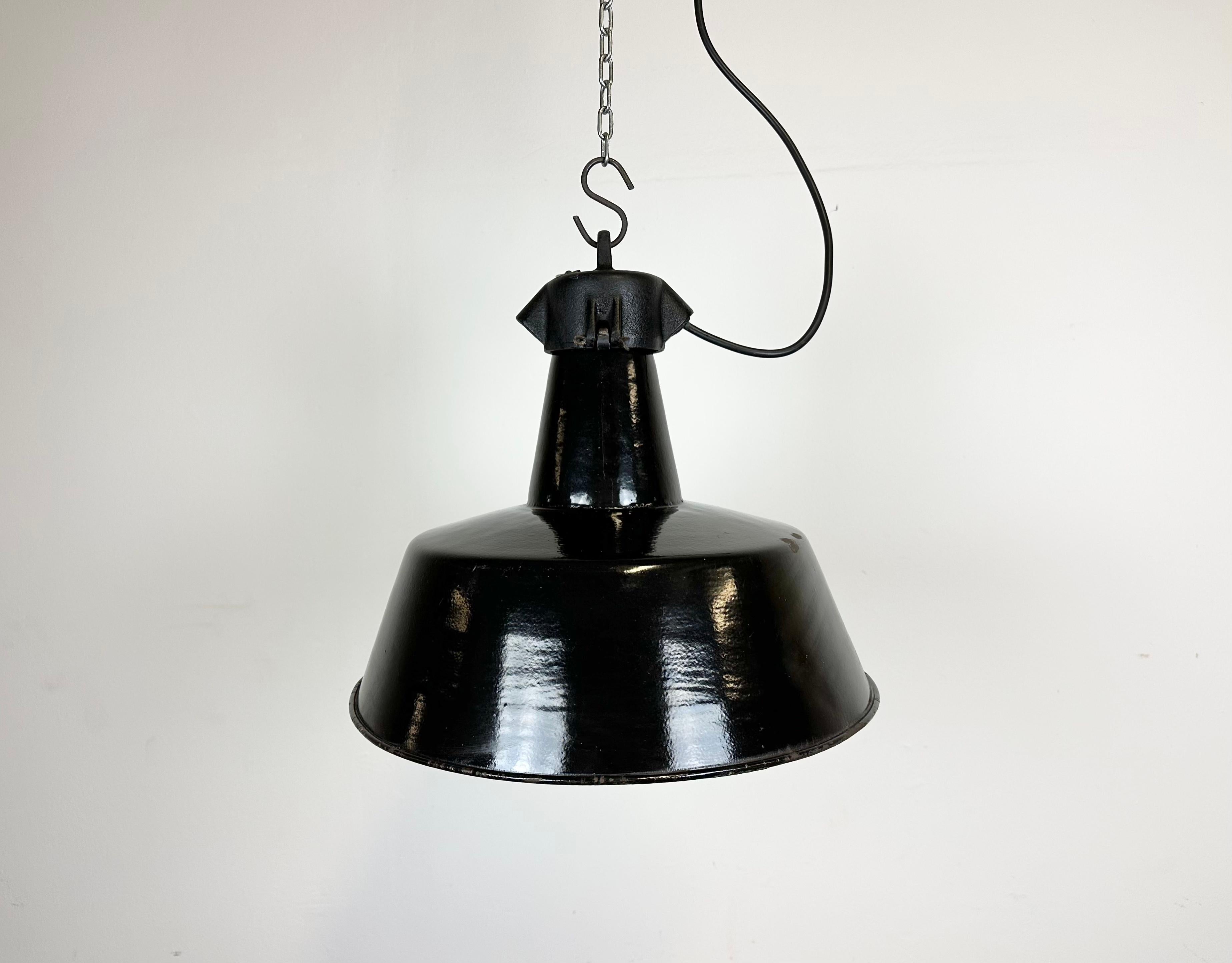 Industrial black enamel pendant light made in former Czechoslovakia during the 1960s. White enamel inside the shade. Cast iron top. The porcelain socket requires E 27/ E26 light bulbs. New wire. Fully functional. The weight of the lamp is 1,8 kg.