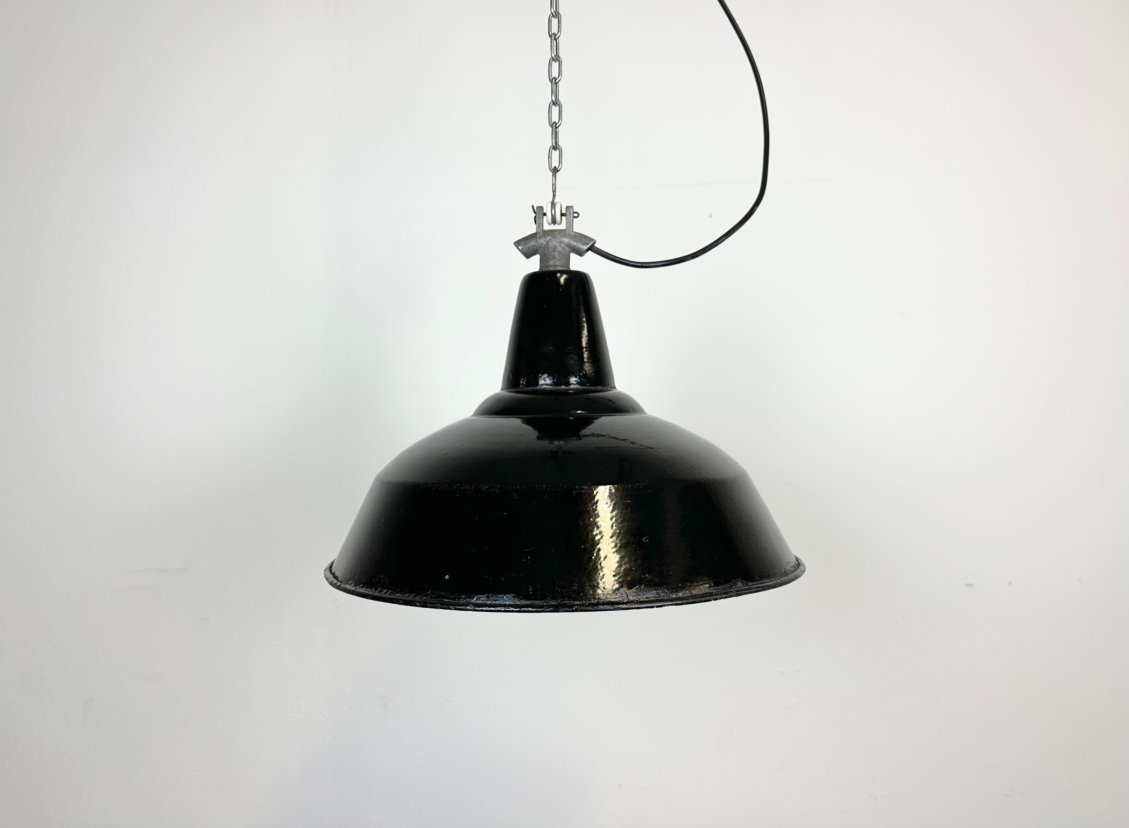 Industrial black enamel pendant light made in former Czechoslovakia during the 1960s. White enamel inside the shade. Cast iron top. The porcelain socket requires E 27/ E26 light bulbs. New wire. Fully functional. The weight of the lamp is 1 kg.