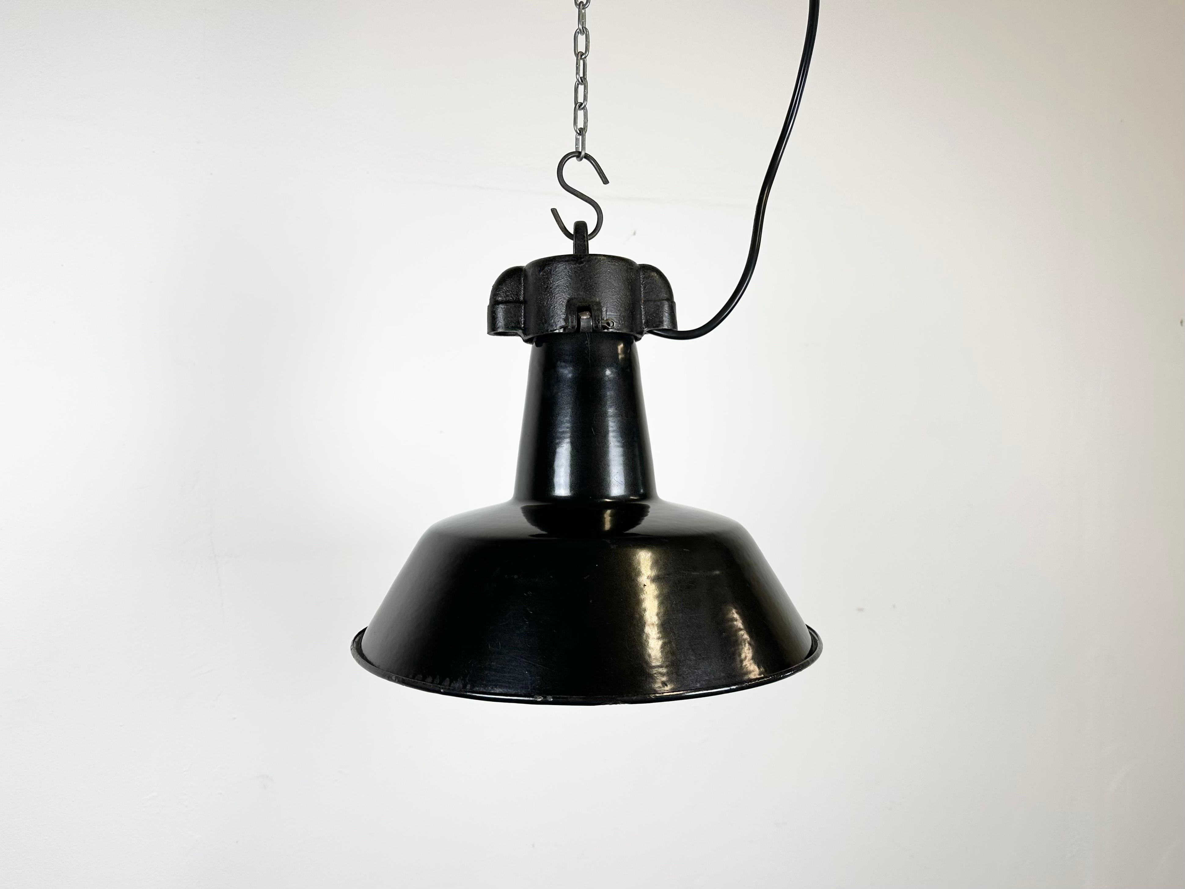 Industrial black enamel pendant light made in former Czechoslovakia during the 1960s. White enamel inside the shade. Cast iron top. The porcelain socket requires E 27/ E26 light bulbs. New wire. Fully functional. The weight of the lamp is 1,5 kg.