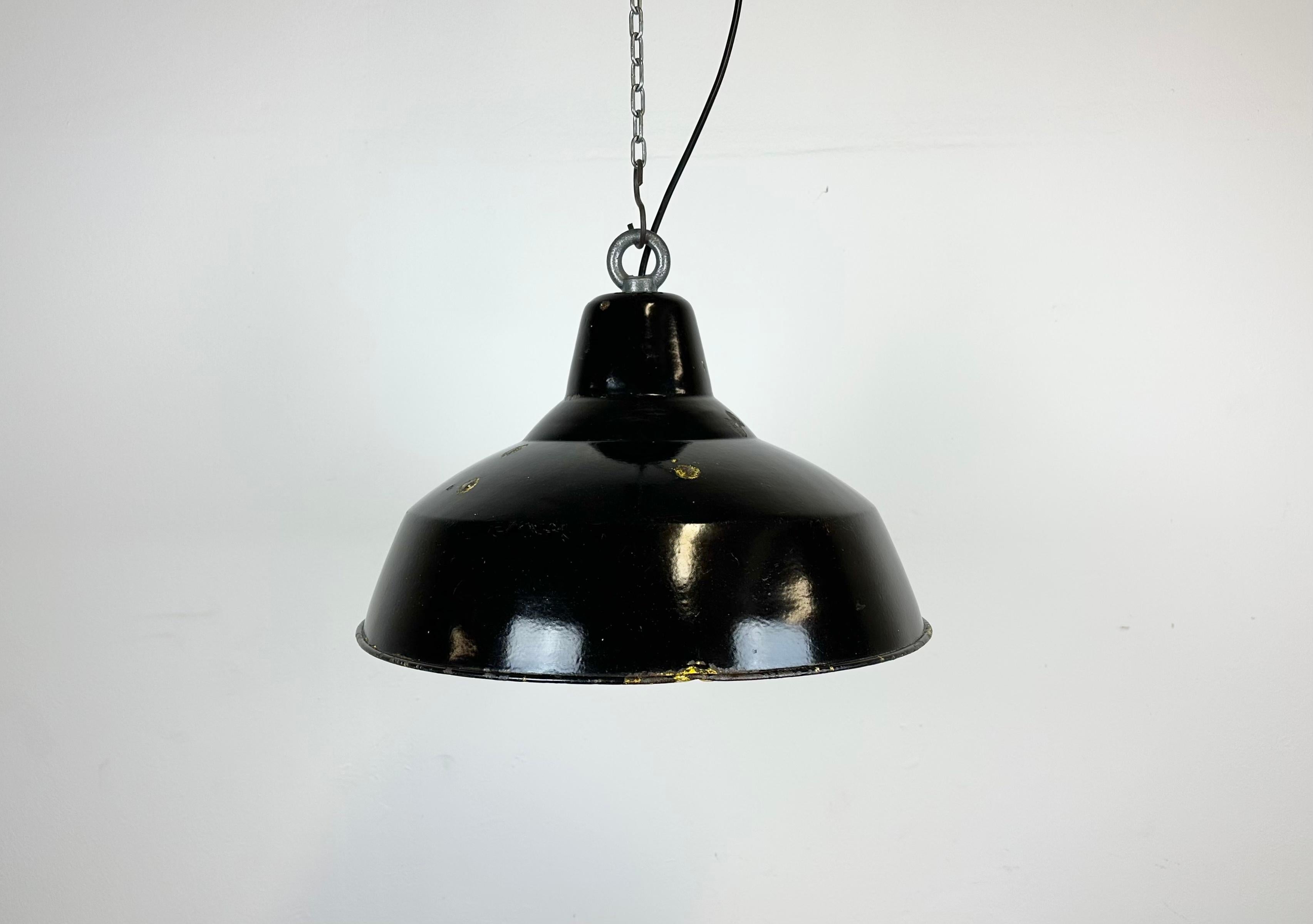 Industrial black enamel pendant light made in former Czechoslovakia during the 1960s. White enamel inside the shade. Iron top. The porcelain socket requires E 27/ E26 light bulbs. New wire. Fully functional. The weight of the lamp is 1,5 kg.