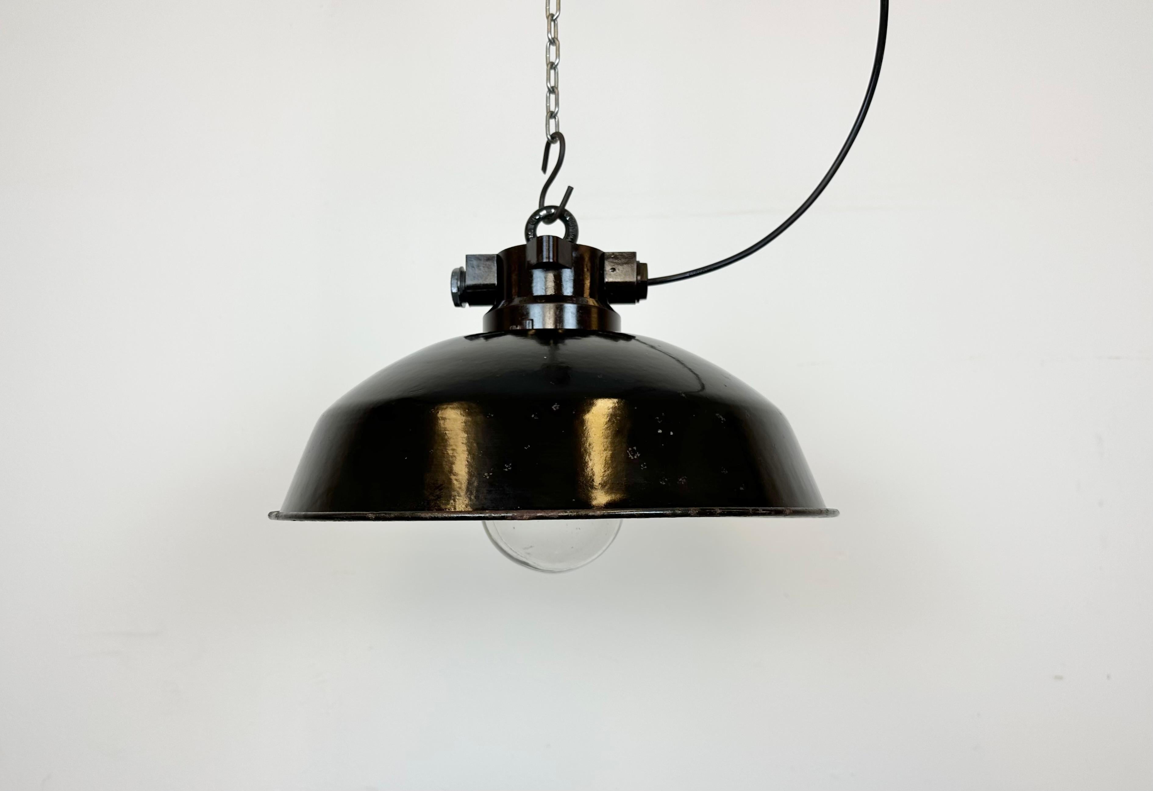 Industrial enamel hanging lamp made in former Czechoslovakia during the 1950s. It features a bakelite top, a black enamel shade with white enamel interior an a clear glass cover. New  socket requires standard E 27/ E 26 light bulbs. New wire. The
