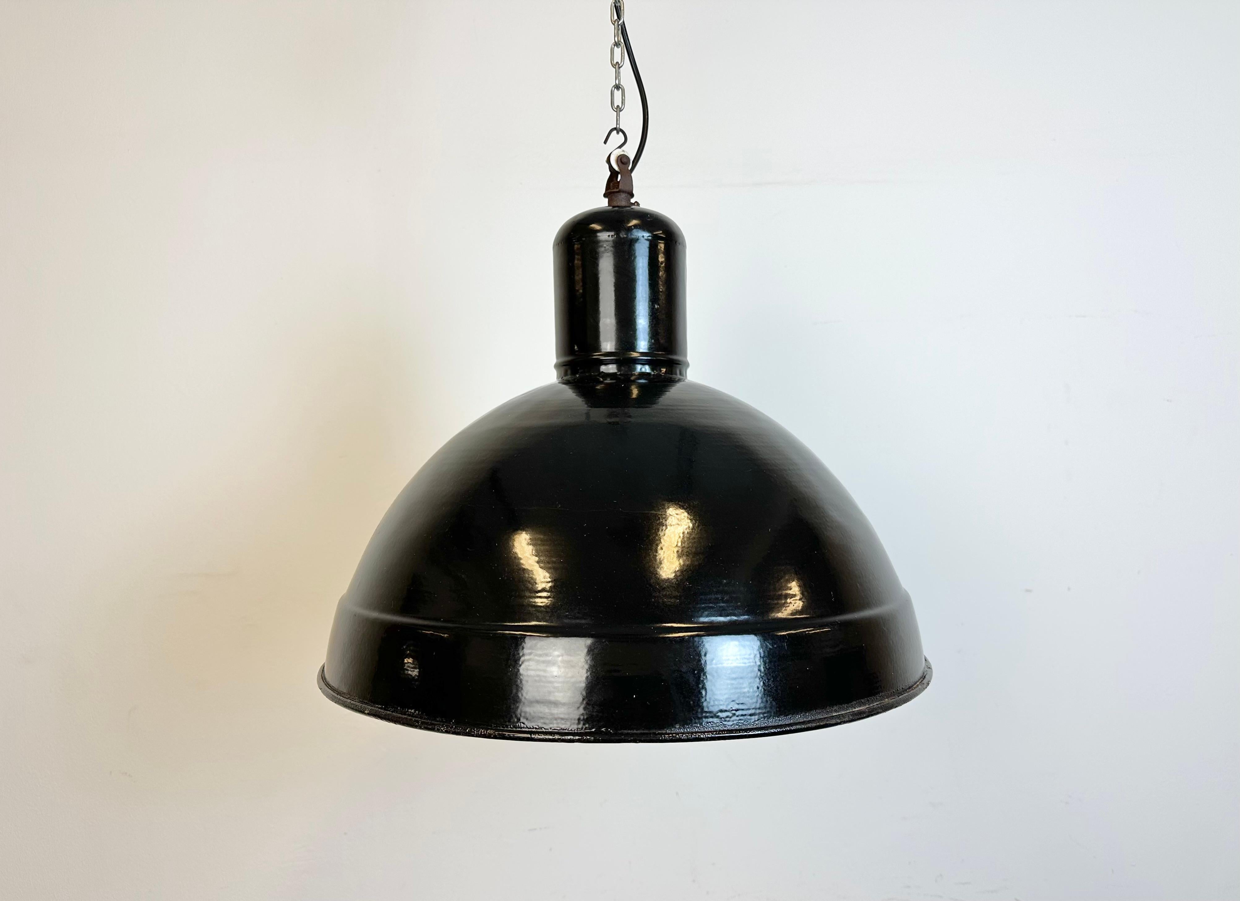 Industrial factory hanging lamp made in former Czechoslovakia during the 1950s. It features a black enamel shade with white enamel interior and an iron top. New  socket requires standard E 27/ E 26 light bulbs. New wire. The lamp weighs 2,4 kg. The