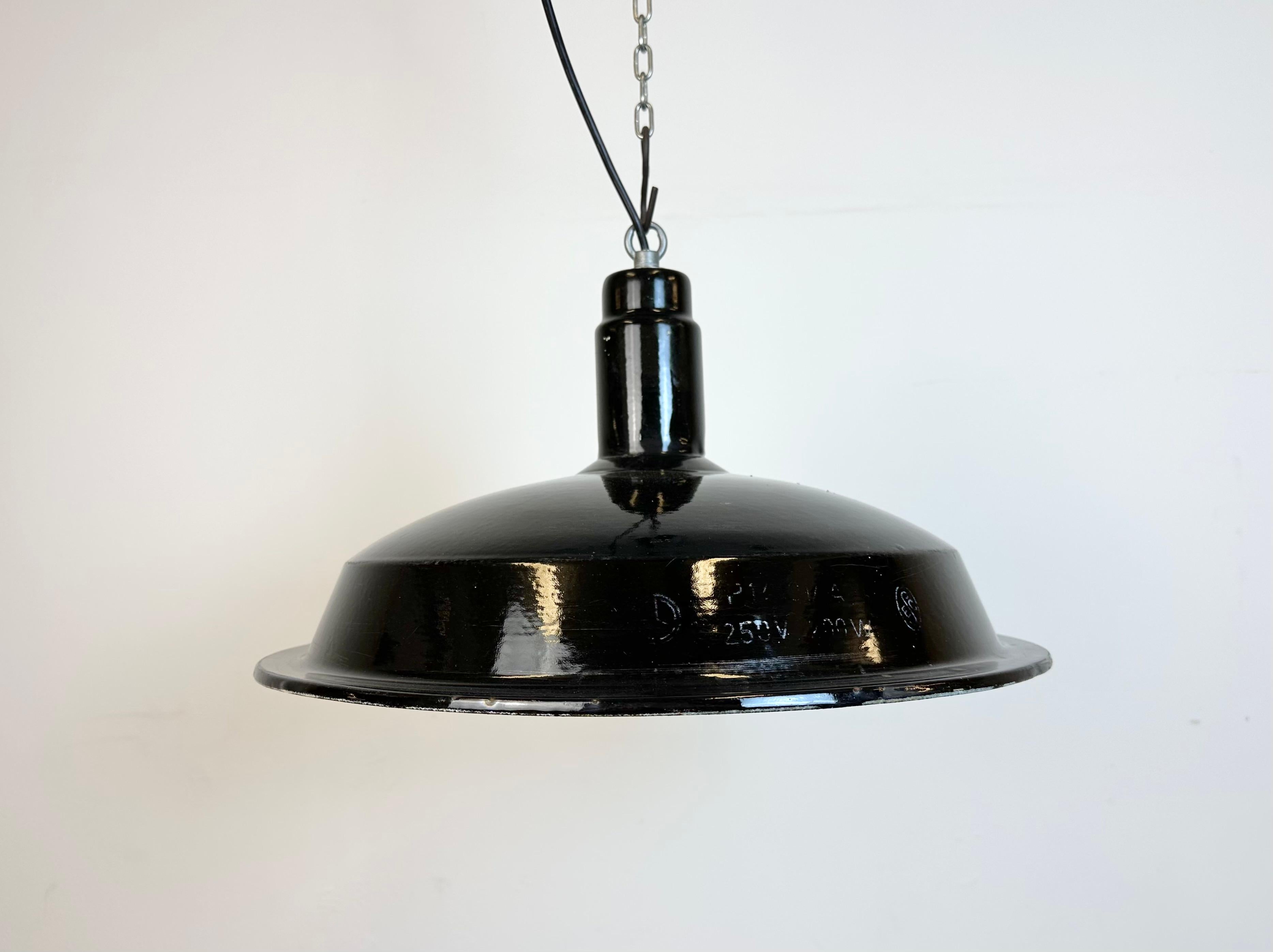 Industrial factory hanging lamp made in former Czechoslovakia during the 1950s. It features a black enamel shade with white enamel interior and an iron top. New  socket requires standard E 27/ E 26 light bulbs. New wire. The lamp weighs 1,3 kg. The