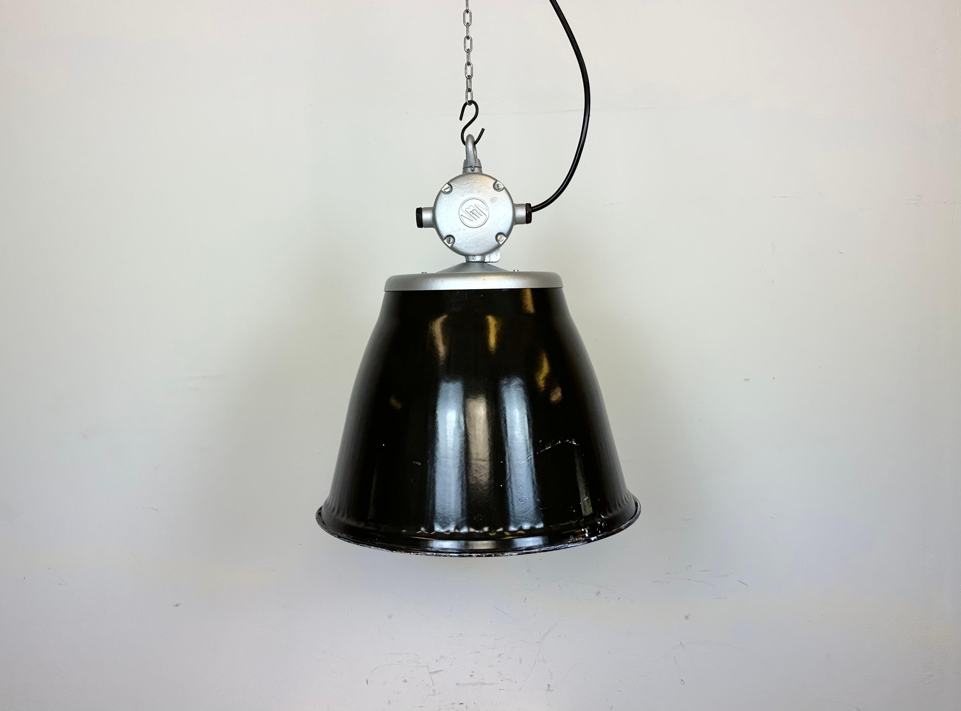 Industrial enamel hanging lamp made by Elektrosvit in former Czechoslovakia during the 1960s. It features a cast aluminium top newly painted on silver and a black enamel shade with white interior. New porcelain socket requires standard E 27/ E 26
