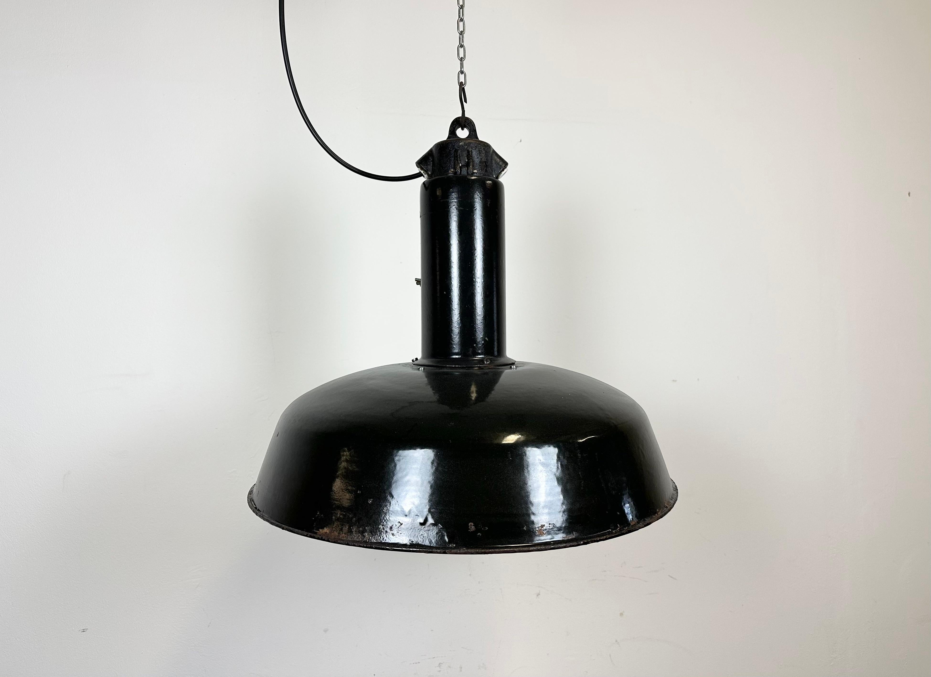 Industrial black enamel pendant light made in former Czechoslovakia during the 1960s. White enamel inside the shade. Cast iron top. The porcelain socket requires E 27/ E26 light bulbs. New wire. Fully functional. The weight of the lamp is 4 kg. Thge