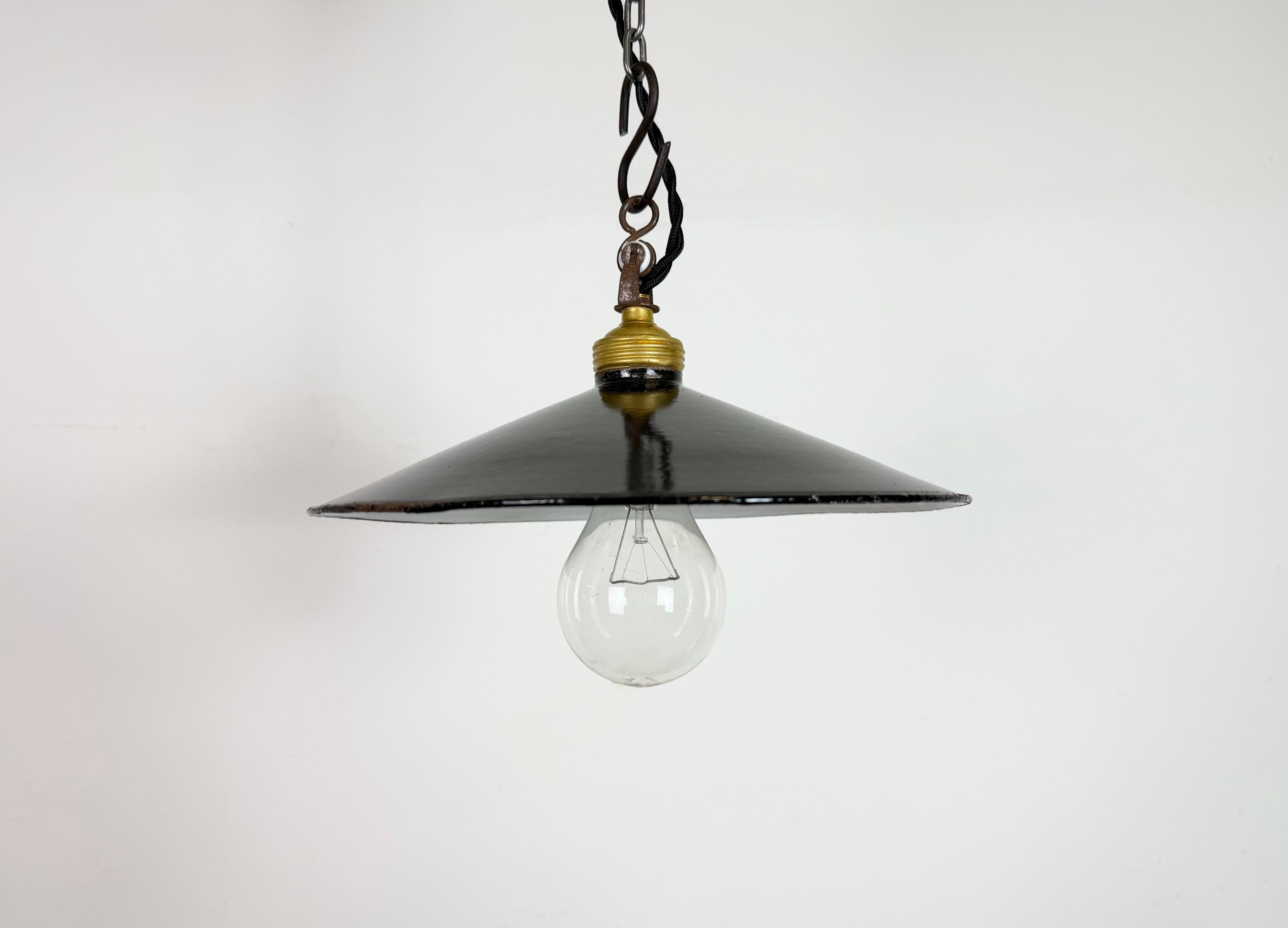 Vintage industrial enamel pendant lamp from the 1930s. It features a black enamel shade with white enamel interior and a brass socket. The socket requires standard E27/ E26 light bulbs. New wire. The weight of the lamp is 0,25kg. The lightbulb is