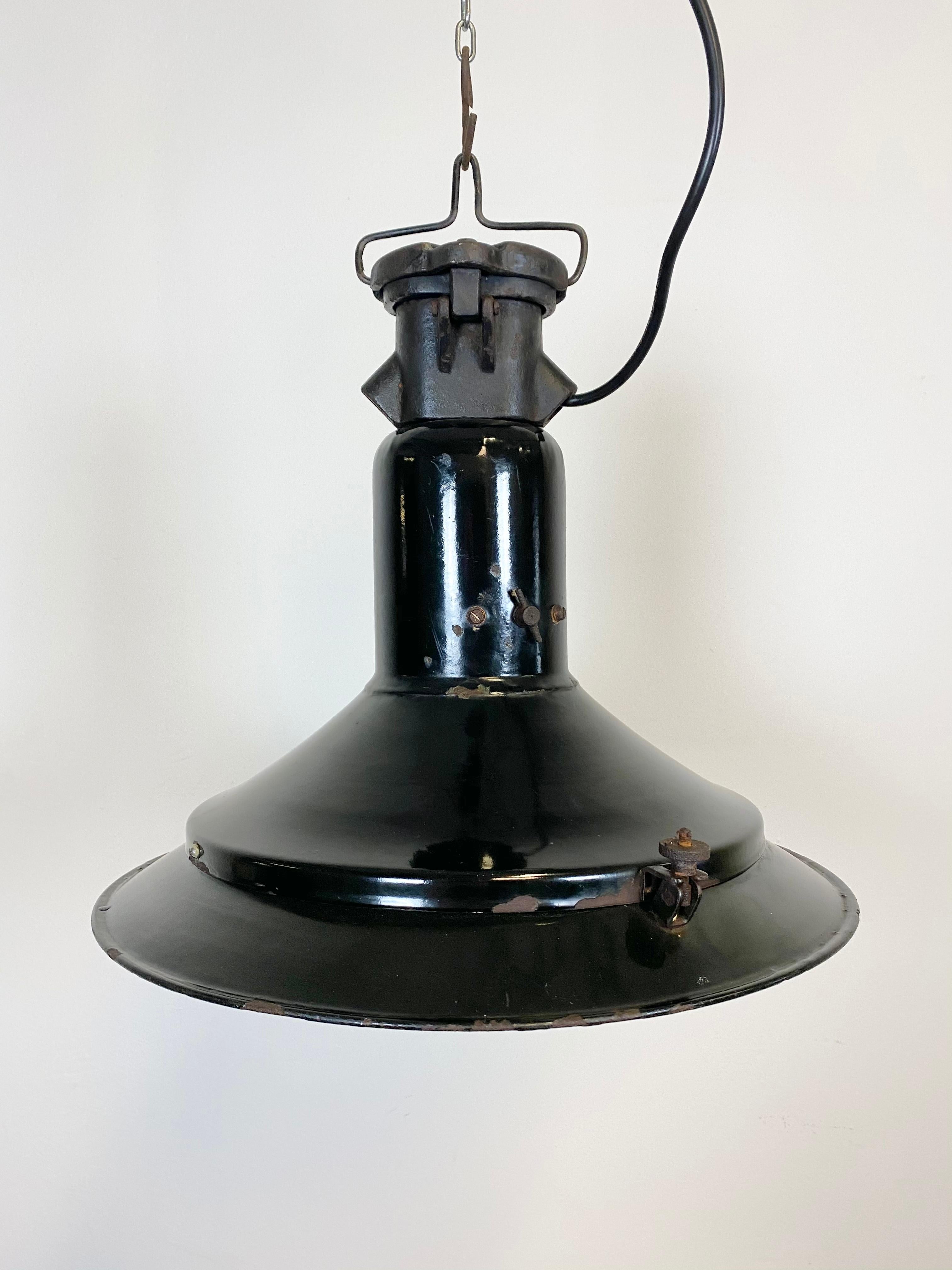 Very old Industrial light made during the 1920s. It features a black enamel exterior, white enamel interior and cast iron top. New porcelain socket for E 27 lightbulbs and wire. Weight : 5 kg.