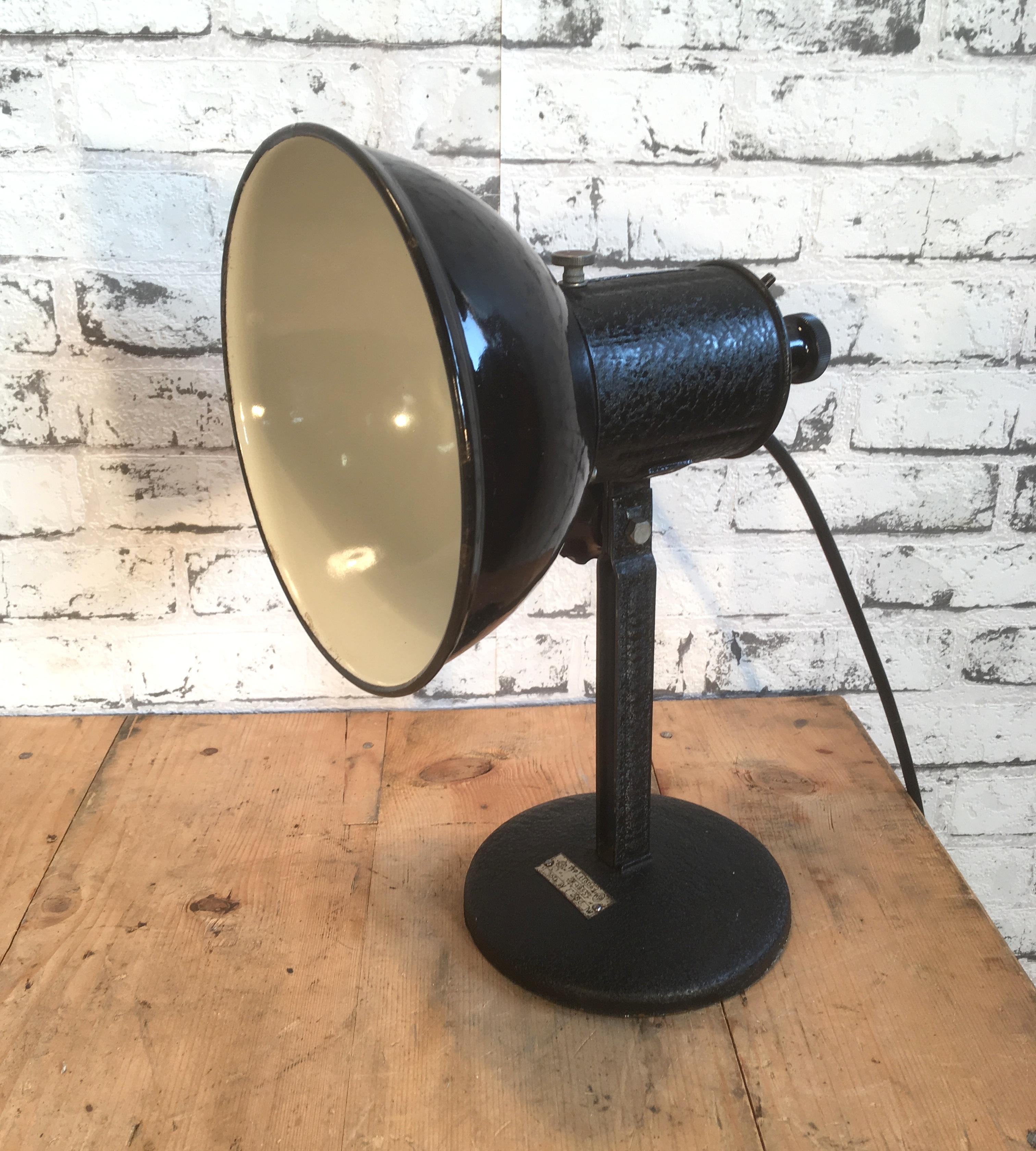 Industrial table lamp from former Czechoslovakia made during the 1950s. It features adjustable black enemal shade, white interior. Iron base. Porcelain socket for E 27 lightbulbs, new wire. Very good vintage condition. Fully functional.