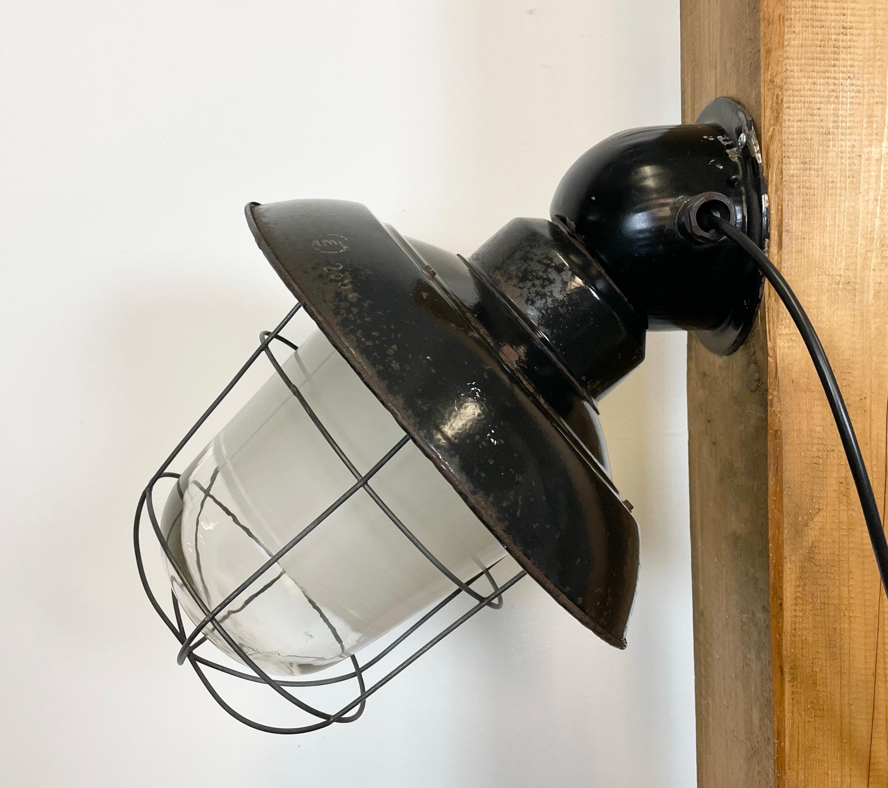 - Industrial wall lamp with iron wall mounting from former Czechoslovakia made during the 1960s
- Black enamel shade with white enamel interior, glass cover, iron grid
- New porcelain socket for E 27 light bulbs and wire
- Weight: 5 kg.